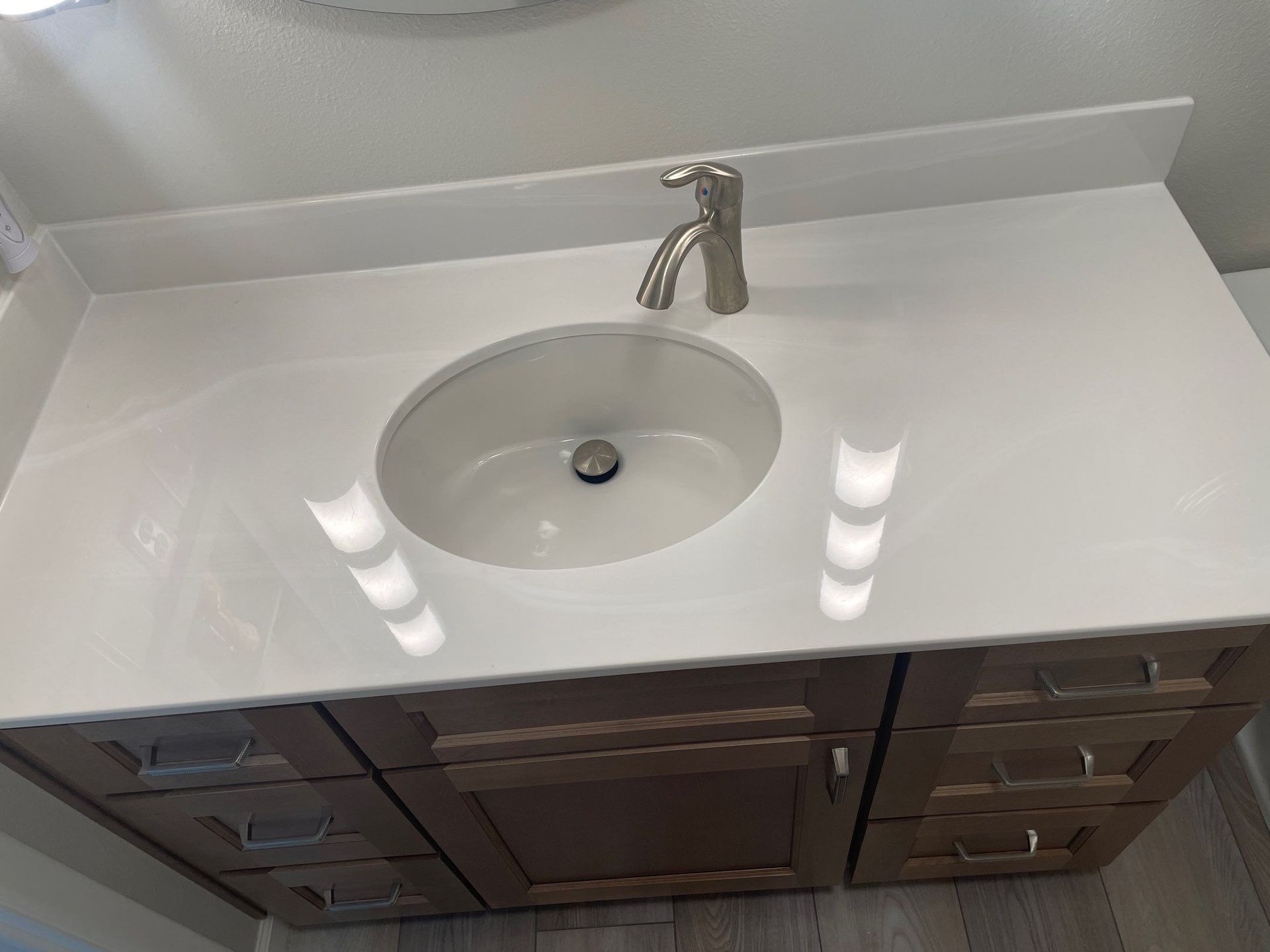 White bathroom vanity with round sink and chrome faucet, viewed from above.