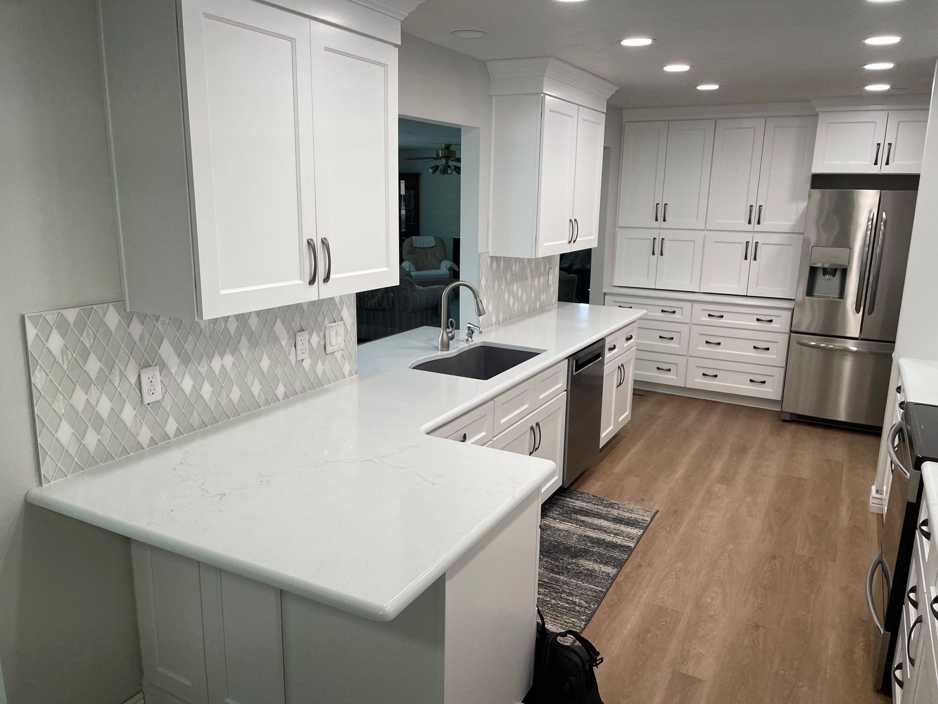 Bright modern kitchen with white cabinets, stainless steel appliances, and wood floors