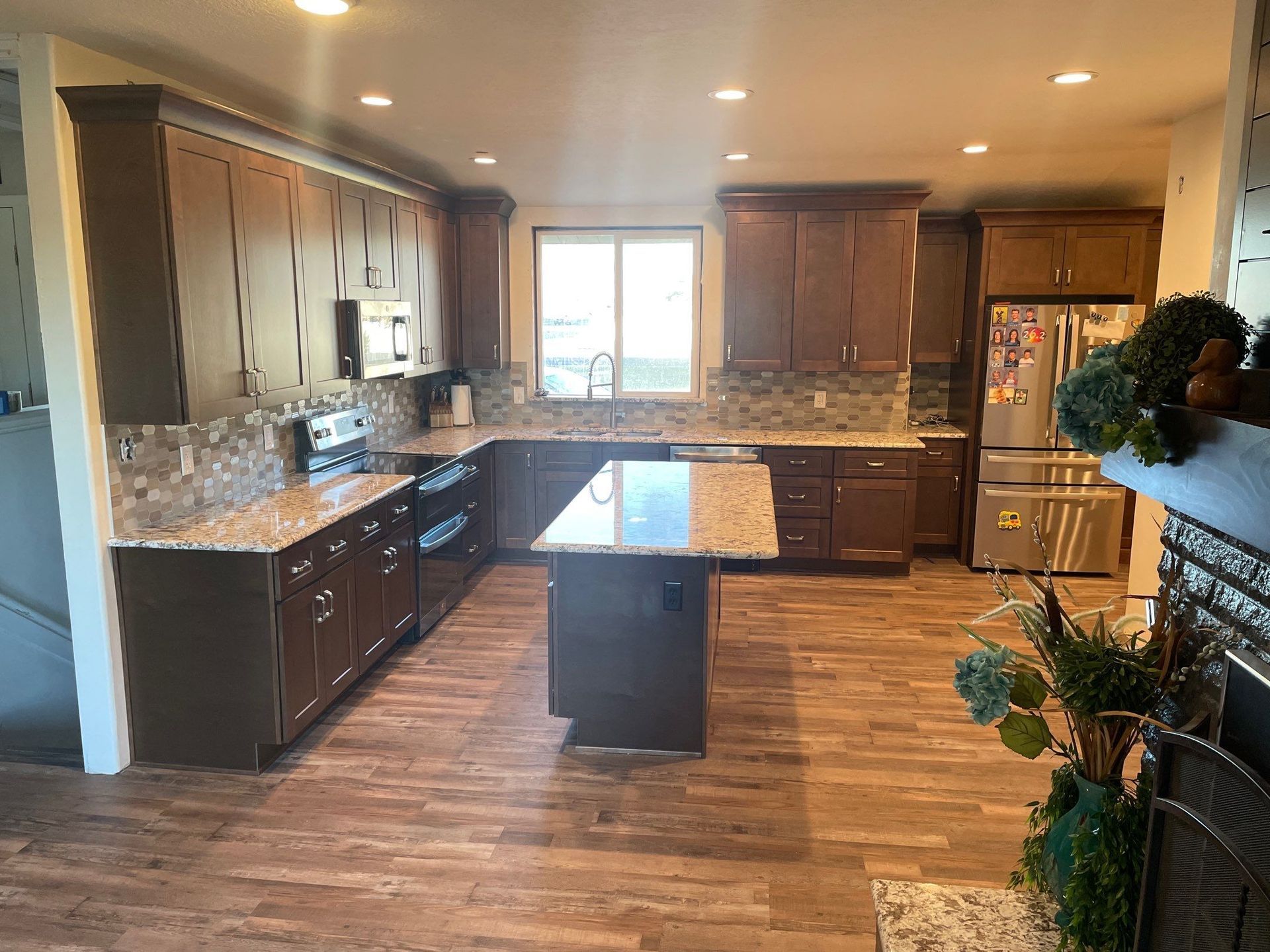 Spacious kitchen with dark wood cabinets, center island, stone backsplash, and wood floors