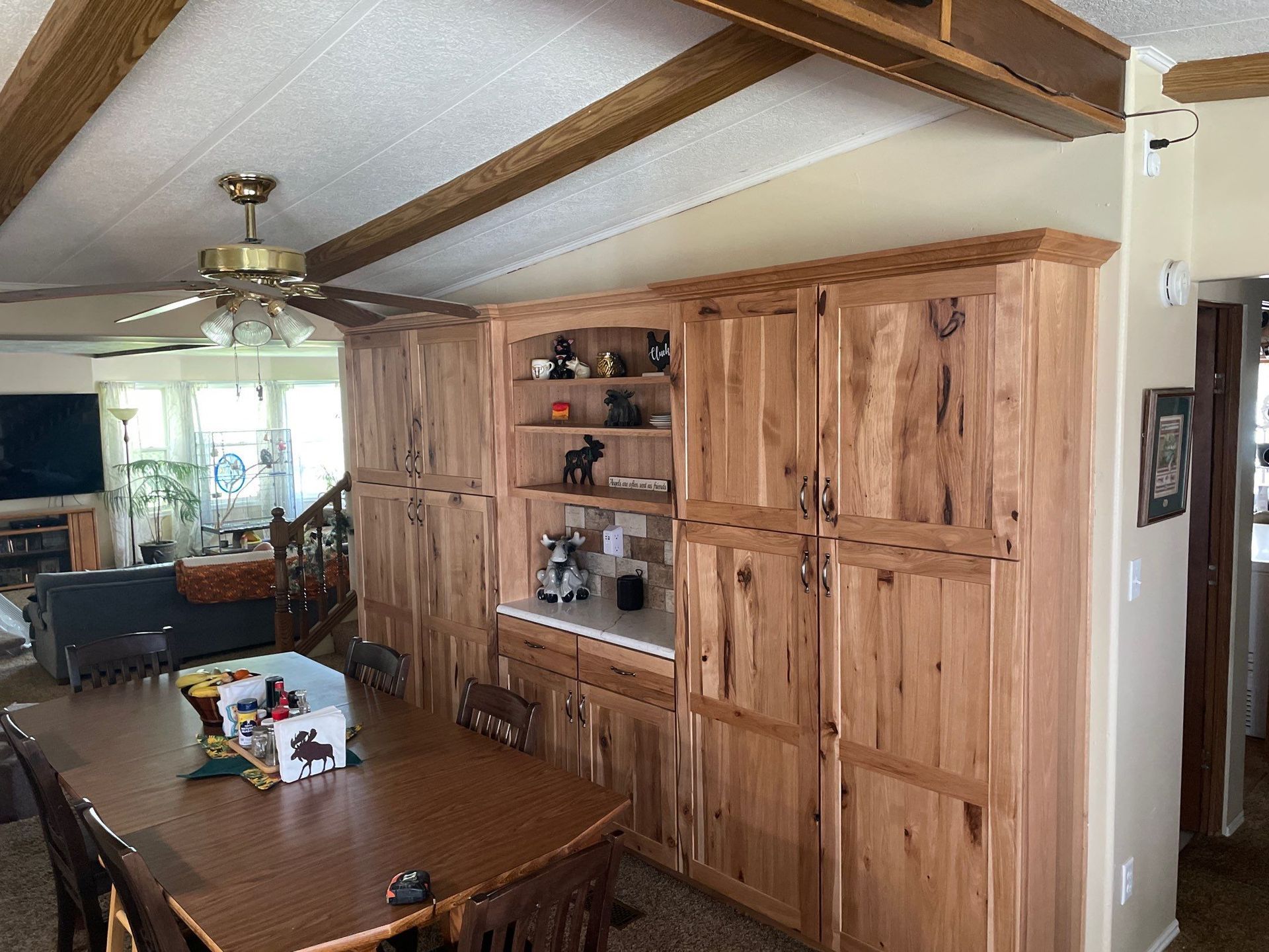Dining room with wood beam ceiling, built-in wooden cabinets, and a dark wood table under a ceiling fan