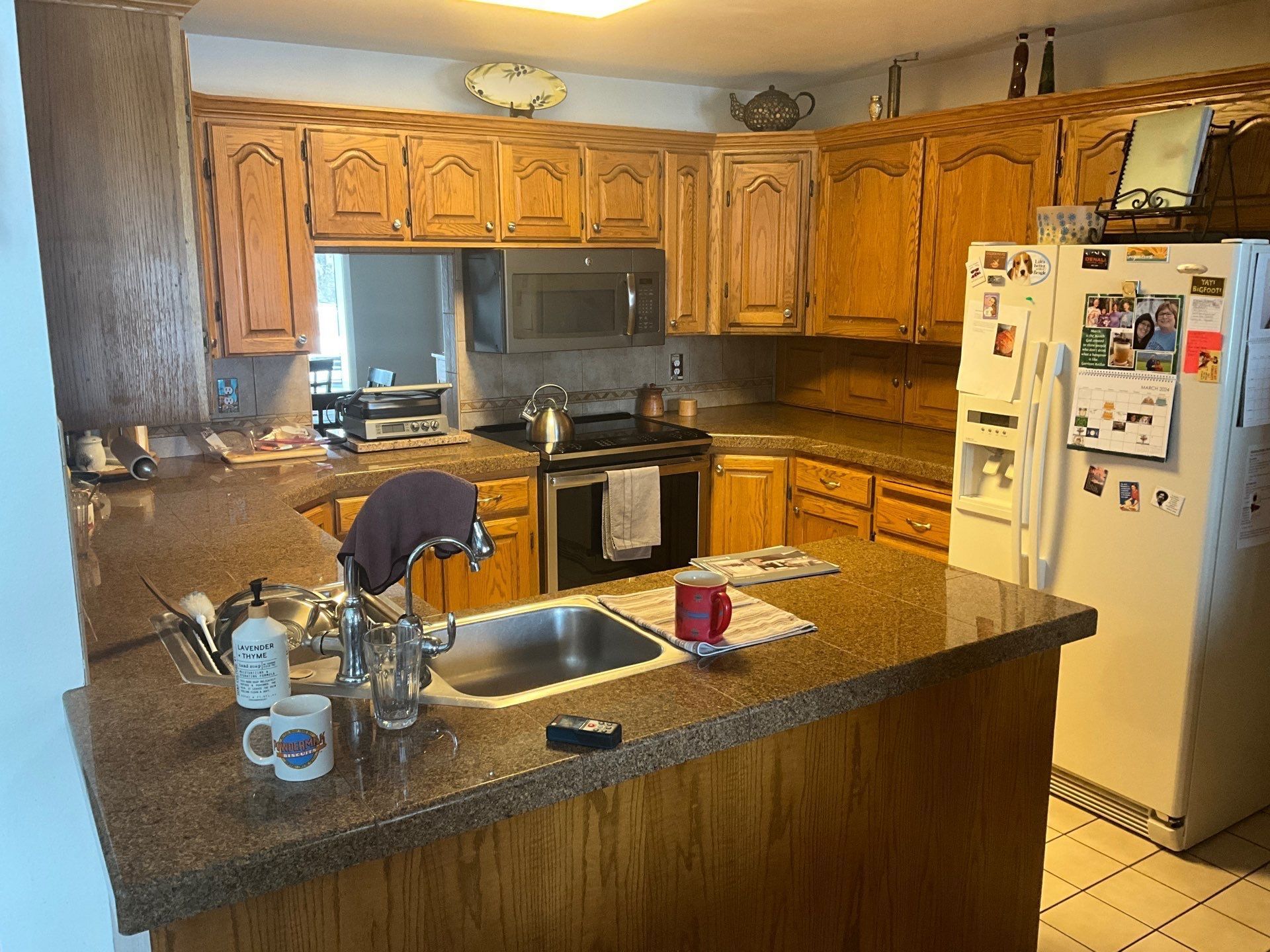 Wooden kitchen with granite island, white refrigerator, and stove under warm lighting.
