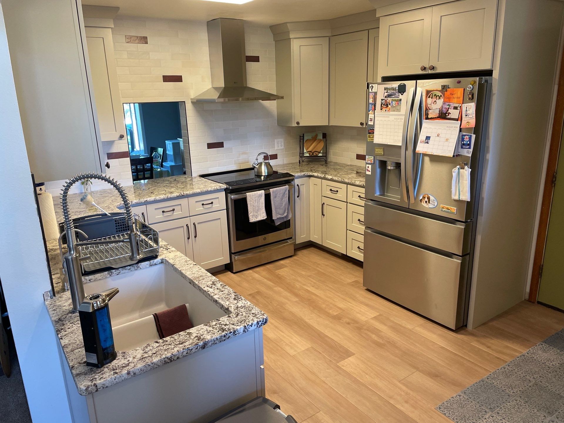 Modern kitchen with white cabinets, stainless steel appliances, granite island, and wood flooring