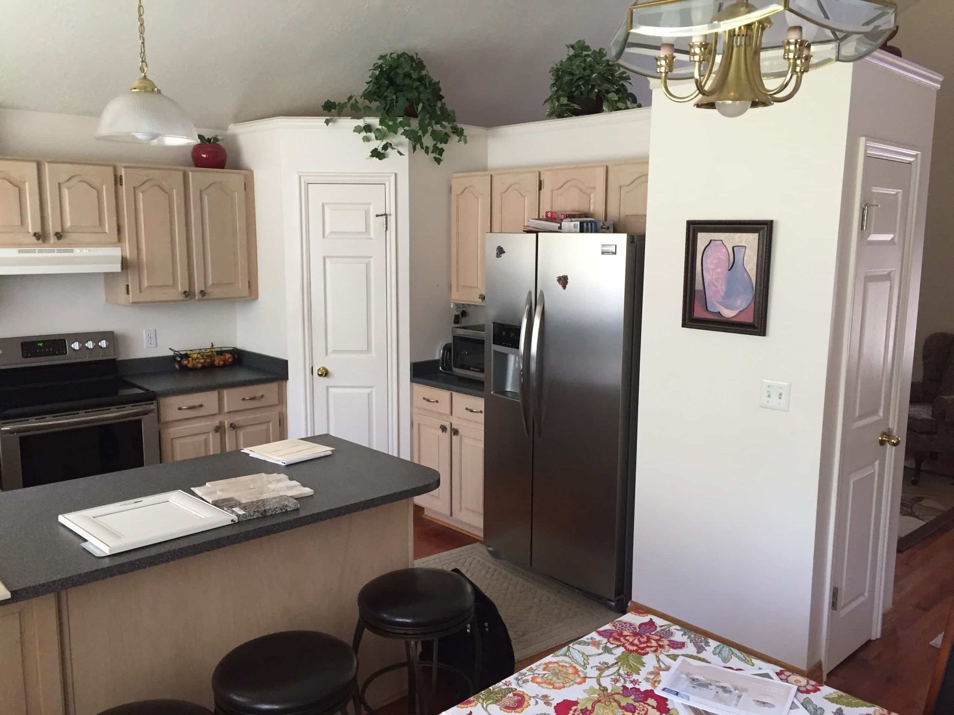 Bright kitchen with island, stools, white cabinets, stainless fridge, and hanging light fixture