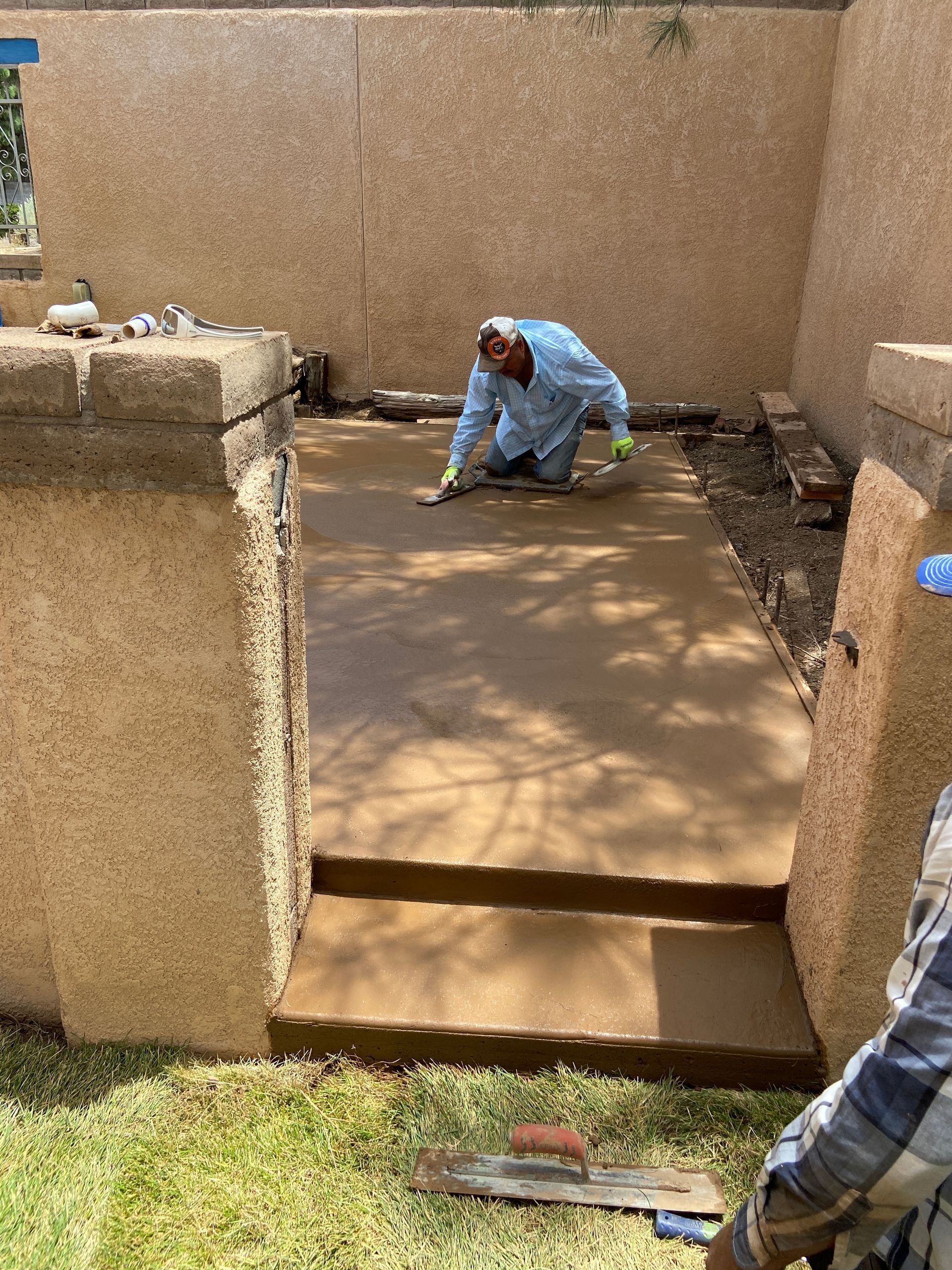 A man is kneeling down on a concrete walkway.