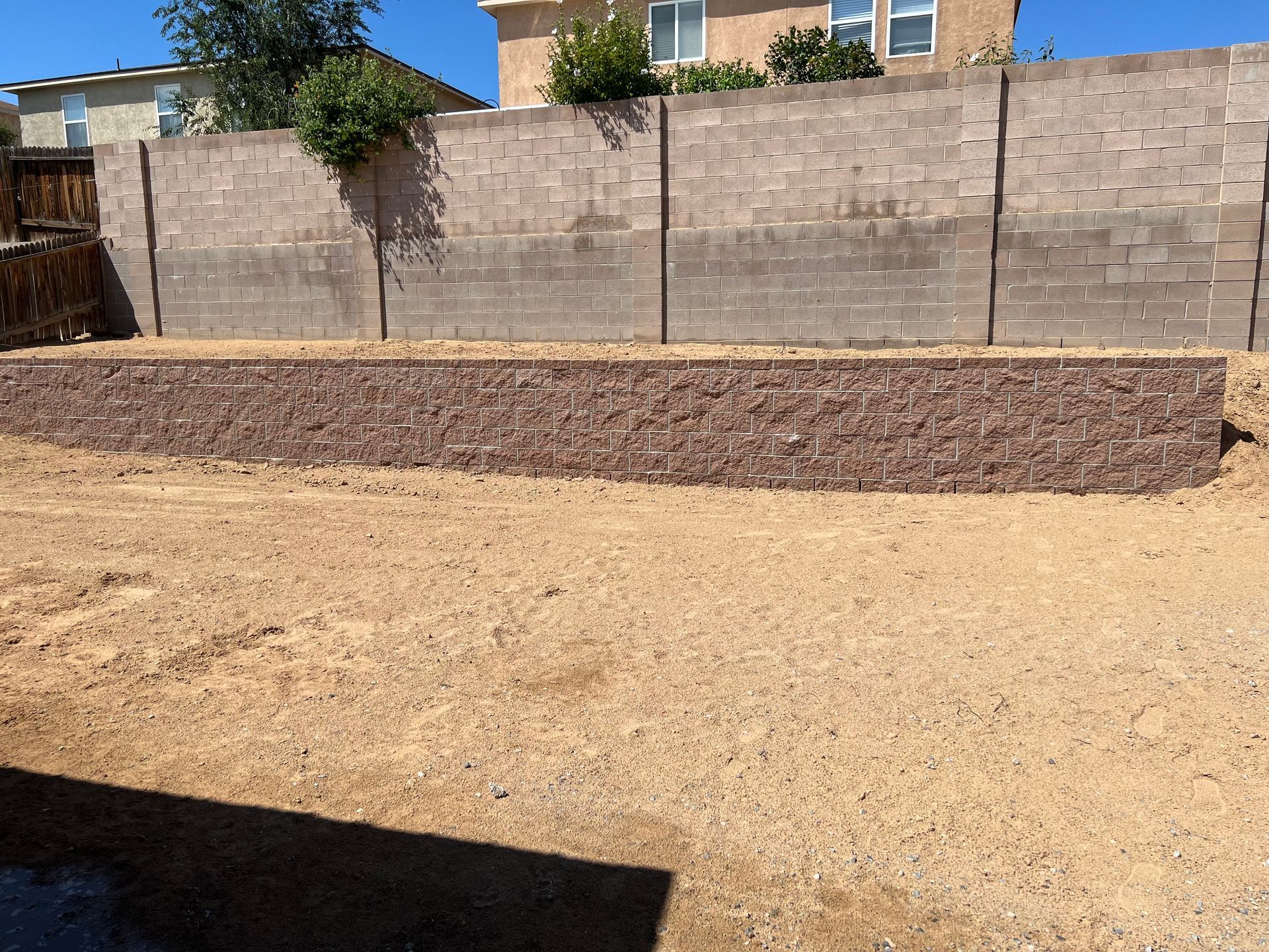 A backyard with a brick wall and a large pile of dirt