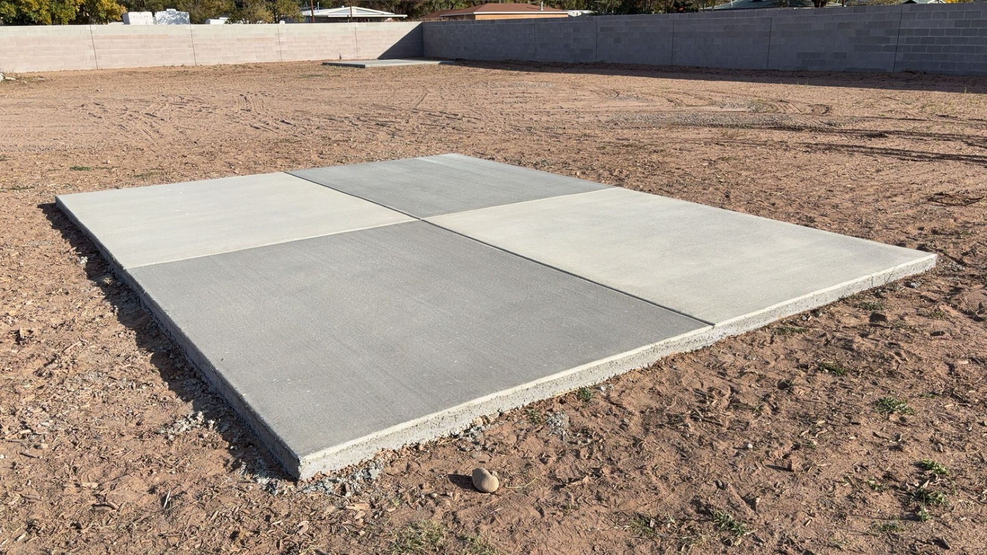 A large concrete slab is sitting on top of a dirt field.