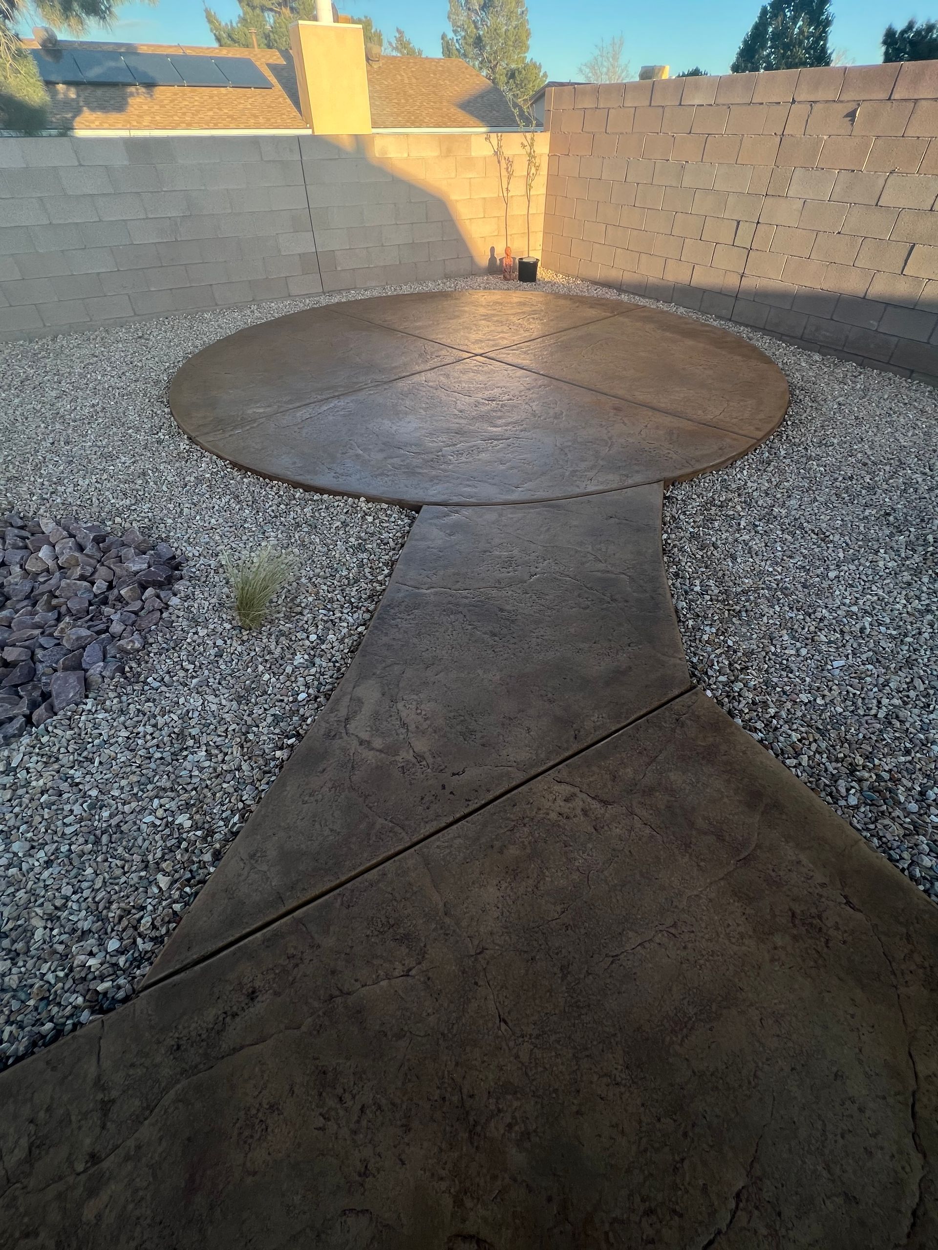 A concrete walkway with a circle in the middle surrounded by gravel.