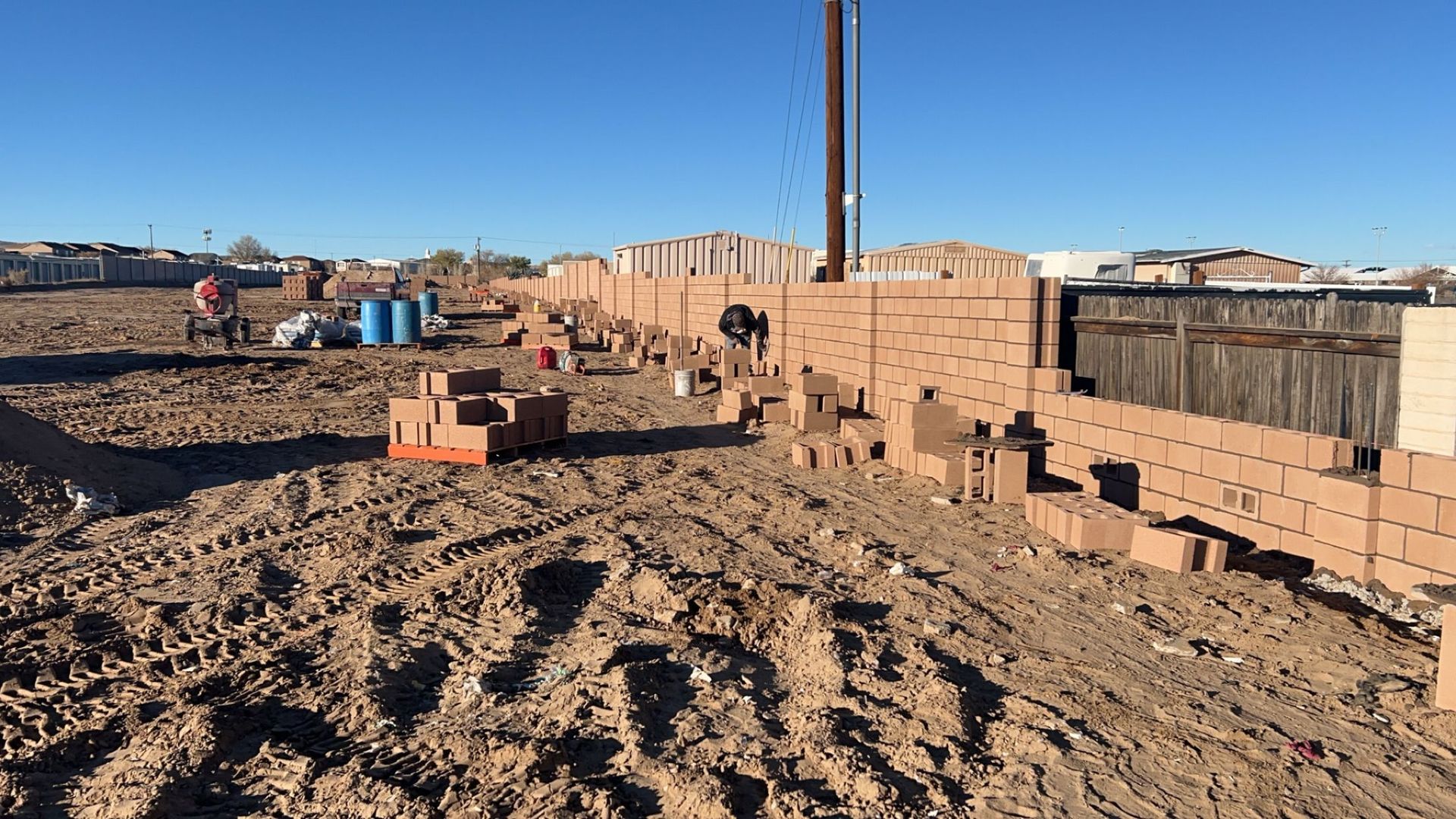 A large pile of bricks is sitting on top of a dirt field.