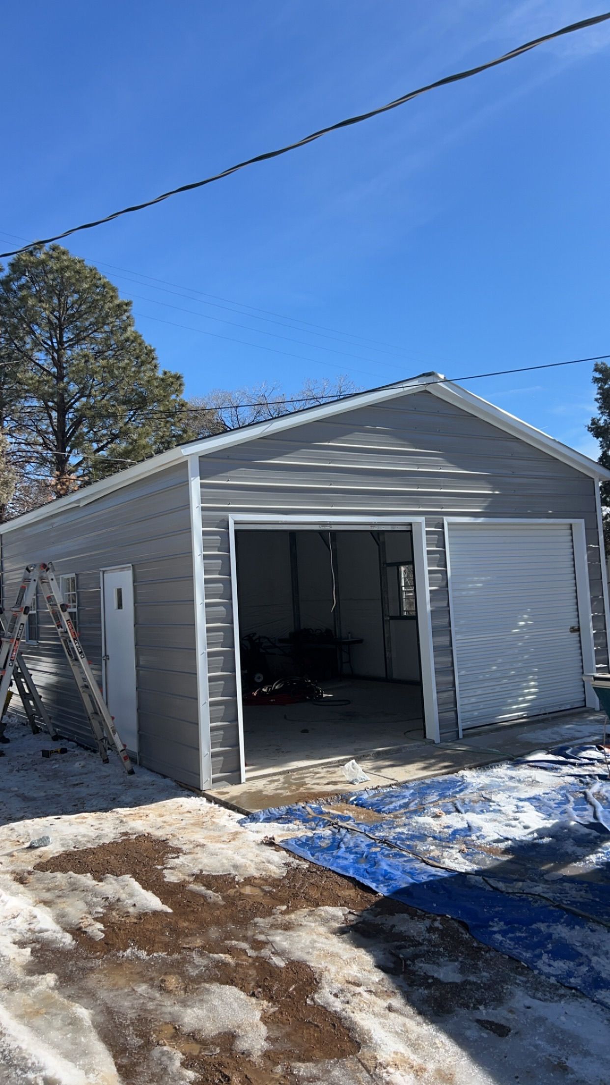 A garage is being built in the snow next to a house.