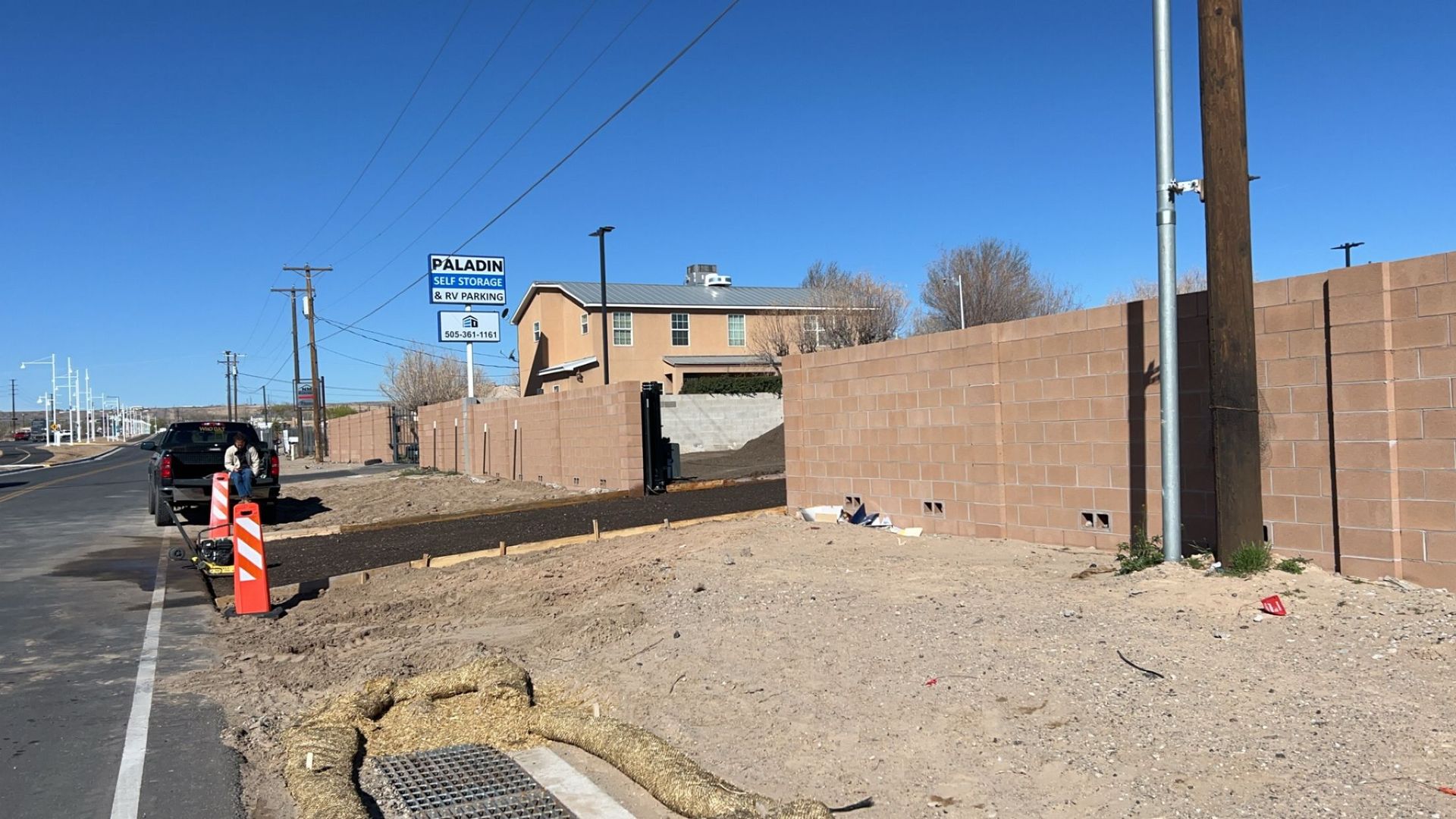 A car is parked on the side of the road next to a brick wall.