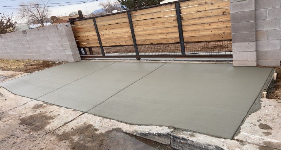 A concrete driveway with a wooden gate in the background.