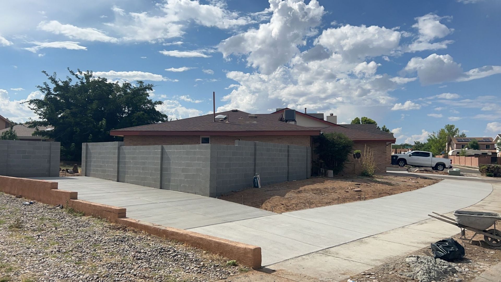 A house with a concrete driveway and a concrete fence in front of it.