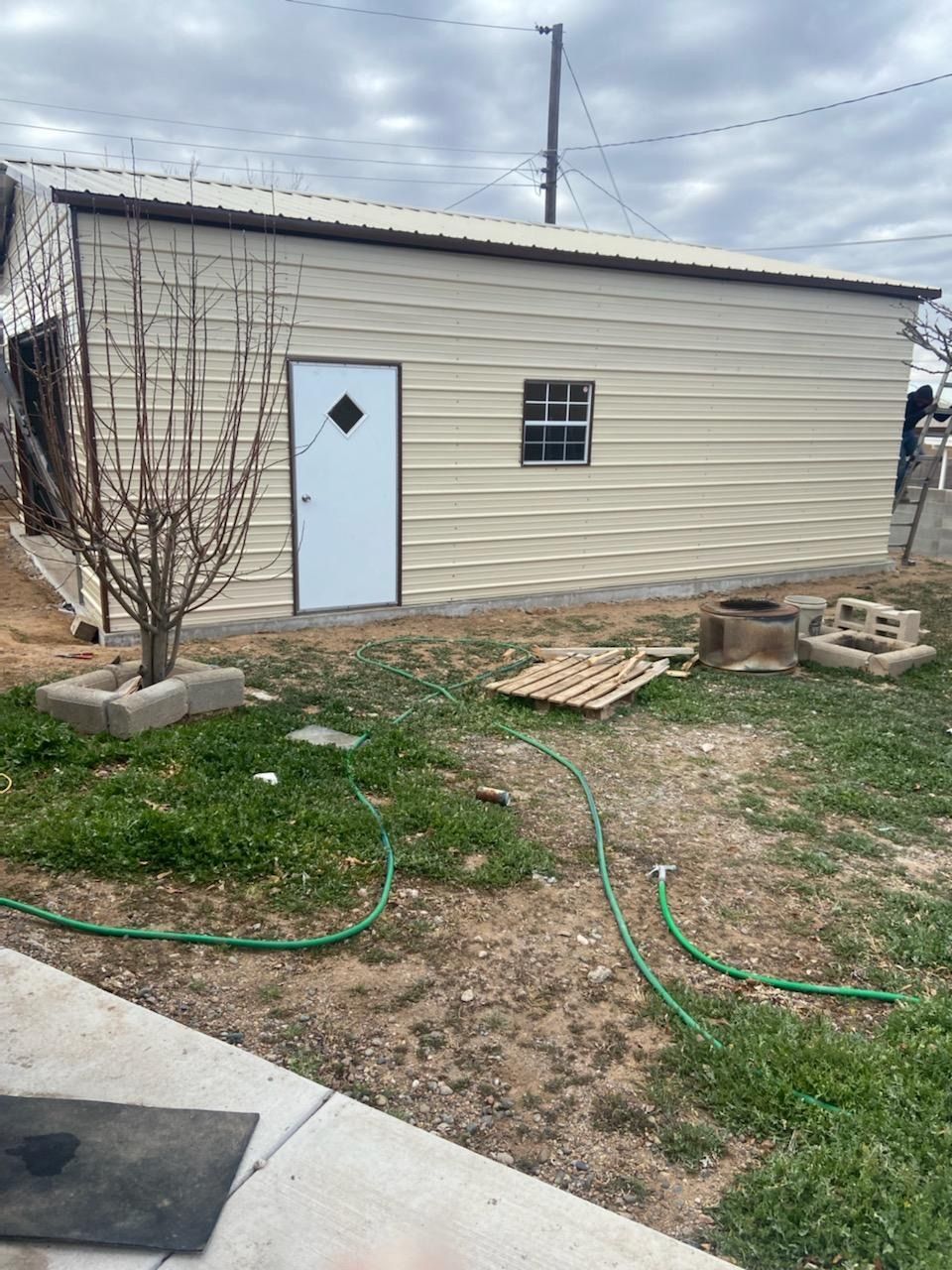 A shed with a blue door and a green hose in the backyard.
