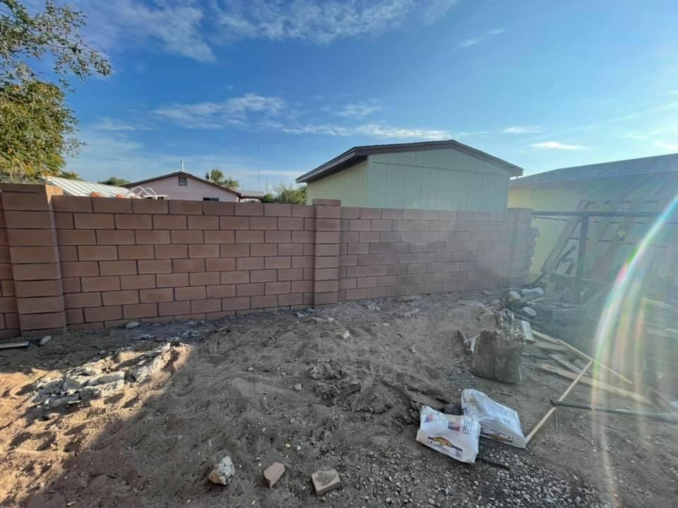 A brick wall is being built in the backyard of a house.