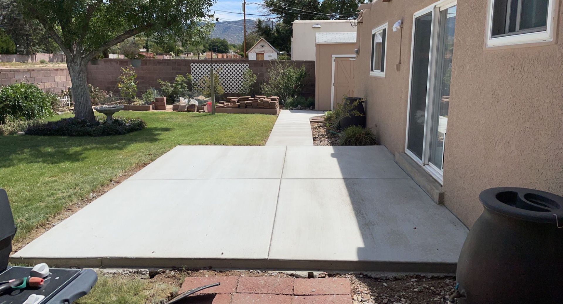 A concrete walkway leading to a house in a backyard.
