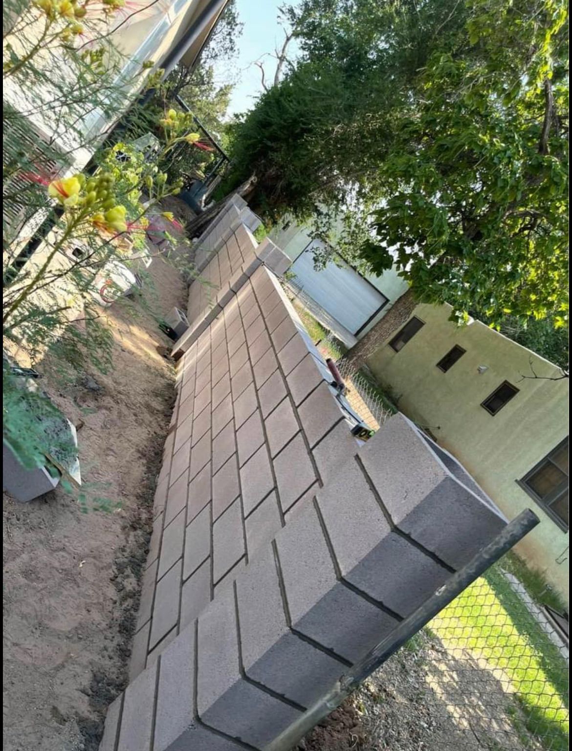 A brick wall is being built in front of a house.