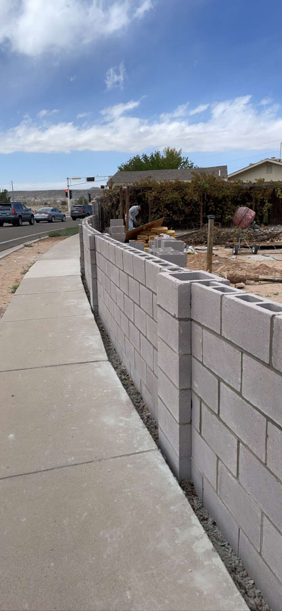 A brick wall is being built next to a sidewalk.