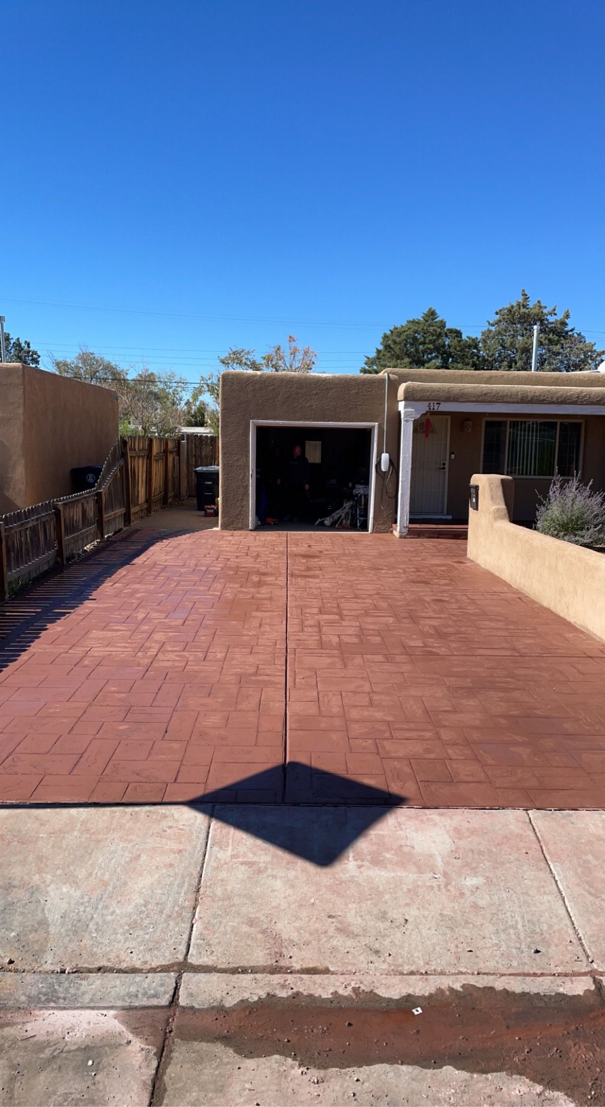 A red driveway leading to a house with a garage.