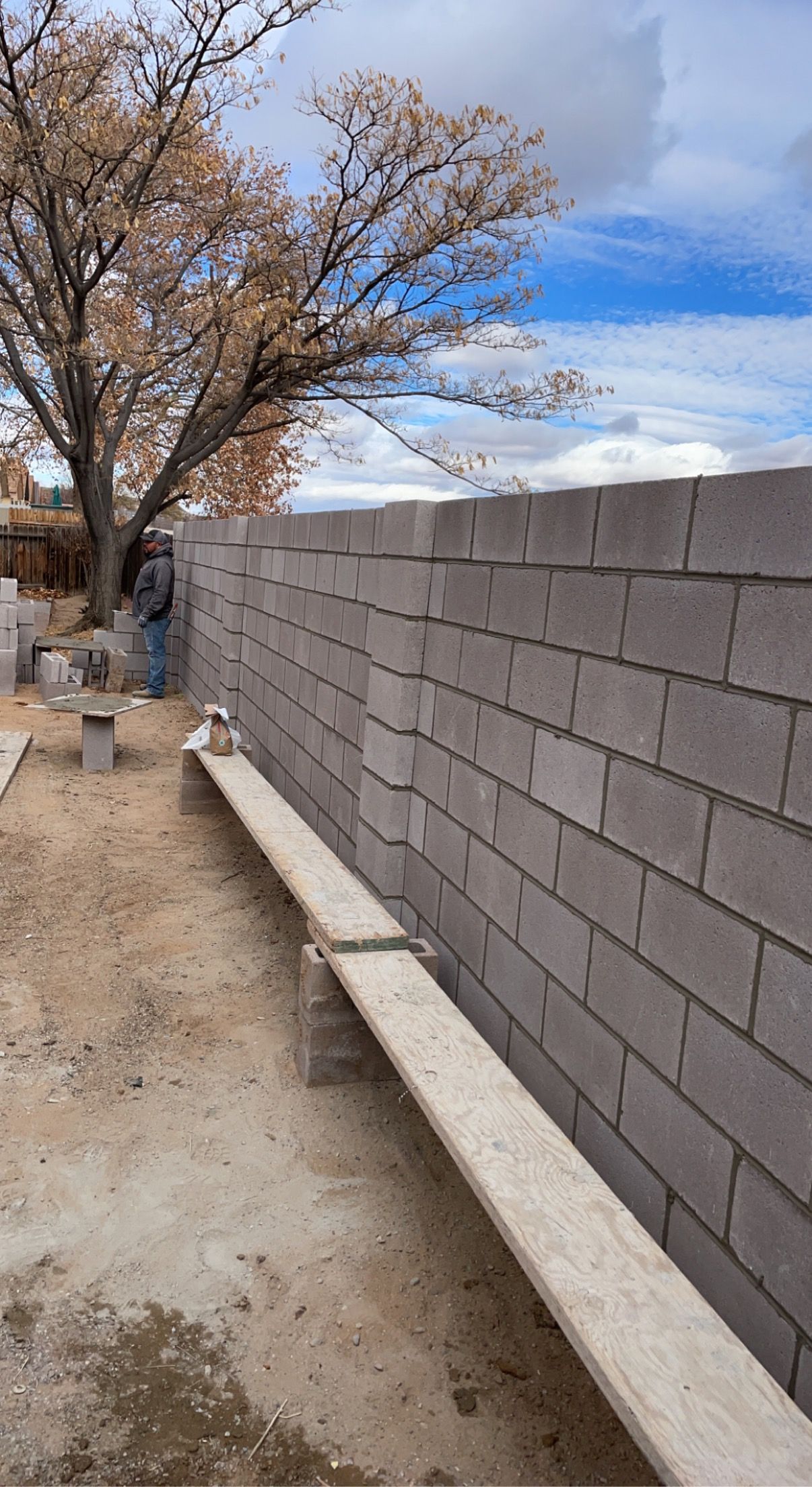 A wooden bench is sitting in front of a brick wall.