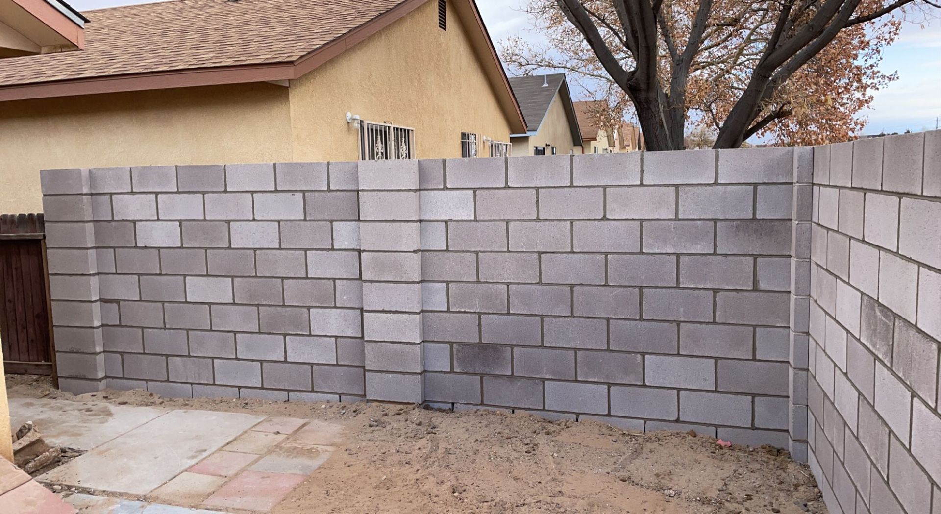 A brick wall is being built in front of a house.