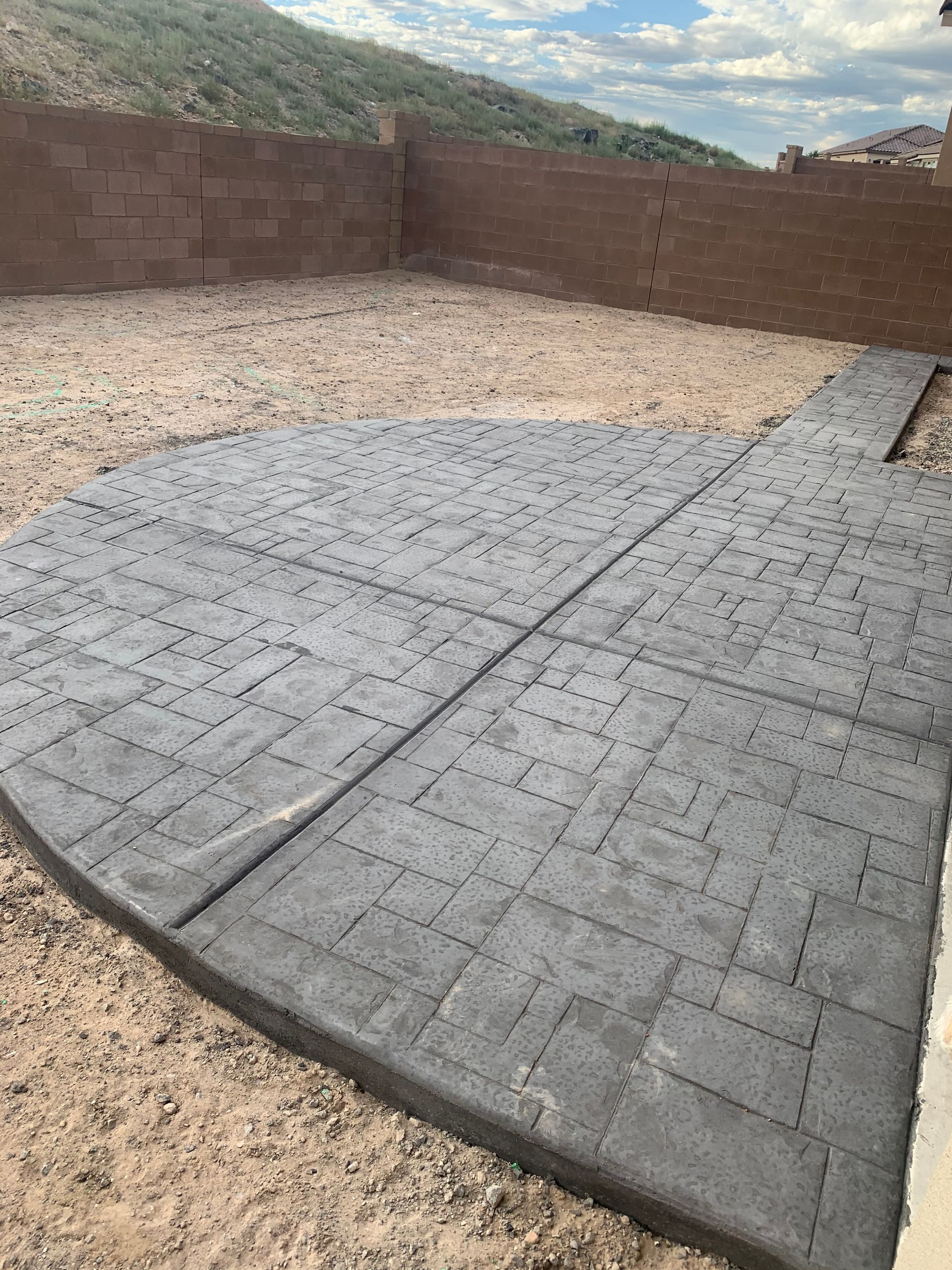 A concrete patio with a brick wall in the background.
