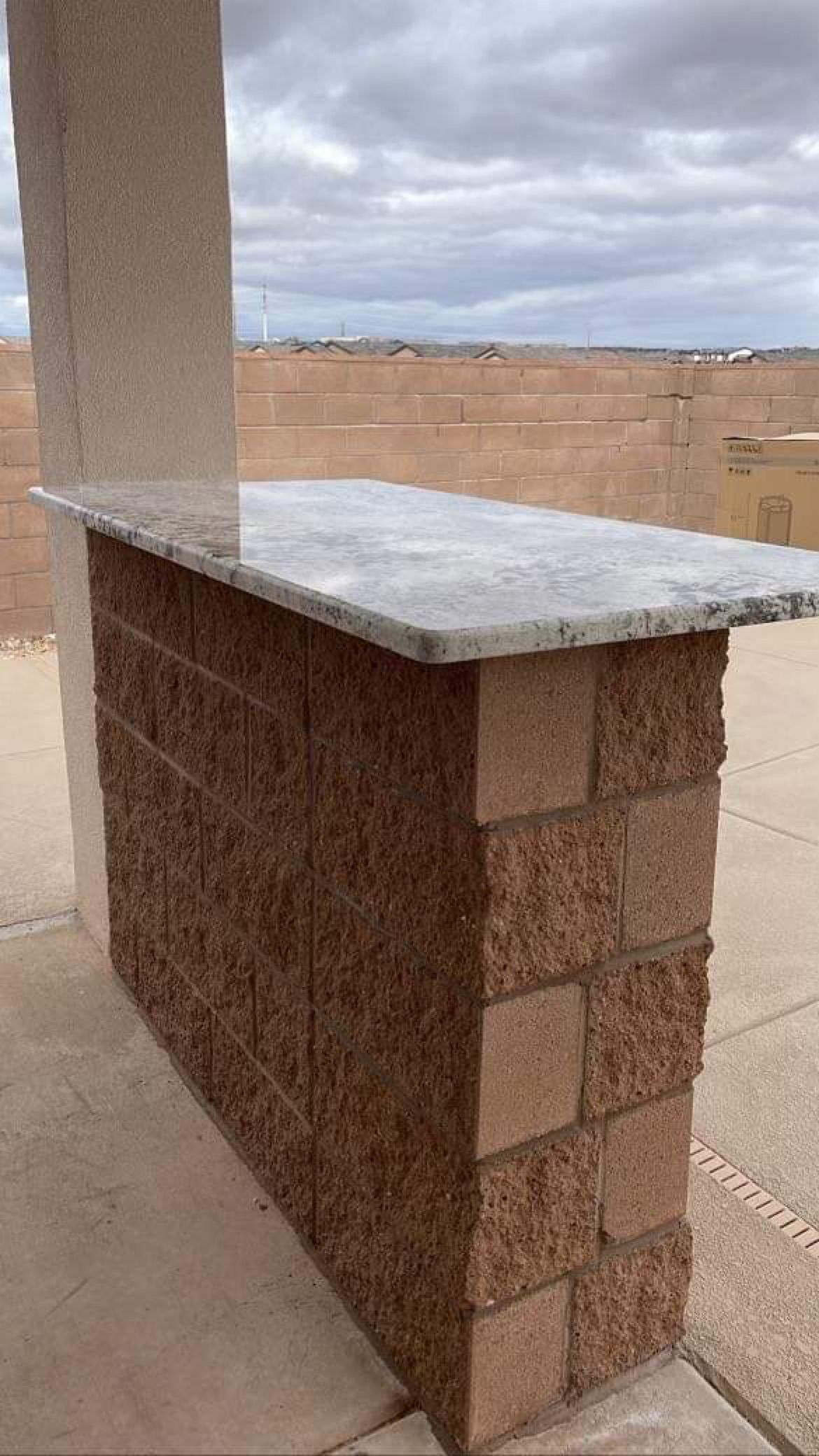 A brick bar with a granite top is sitting on a sidewalk.