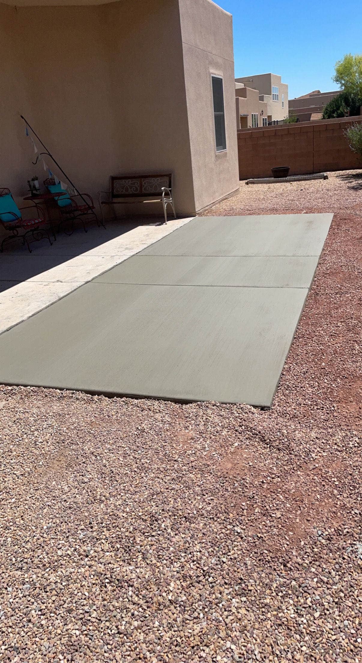 A large concrete slab is sitting on top of a gravel driveway in front of a house.
