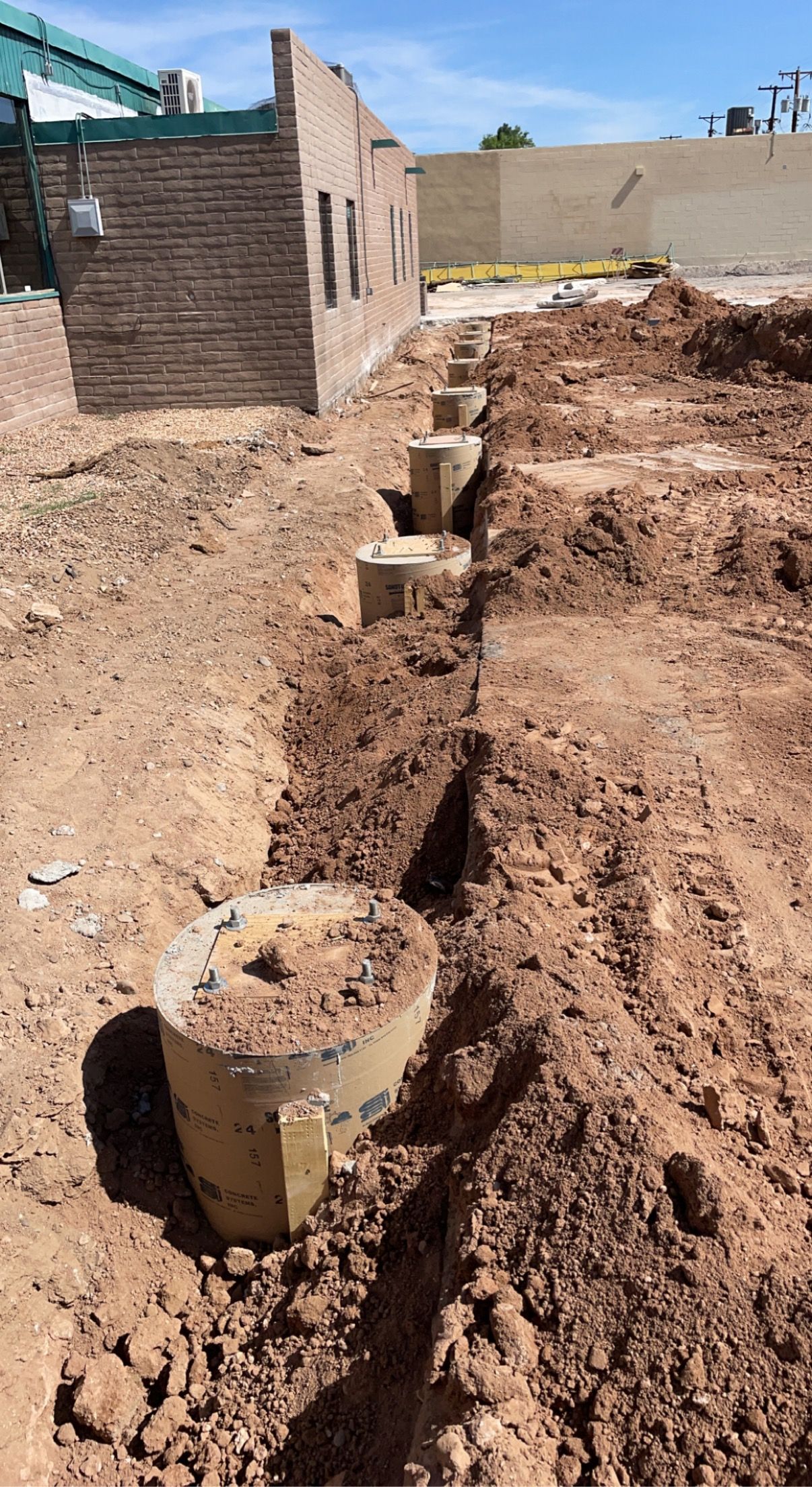 A dirt field with a brick building in the background.