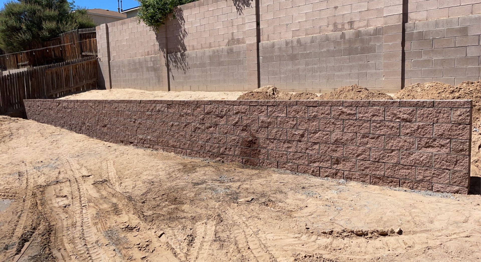 A brick wall is being built in the middle of a dirt field.