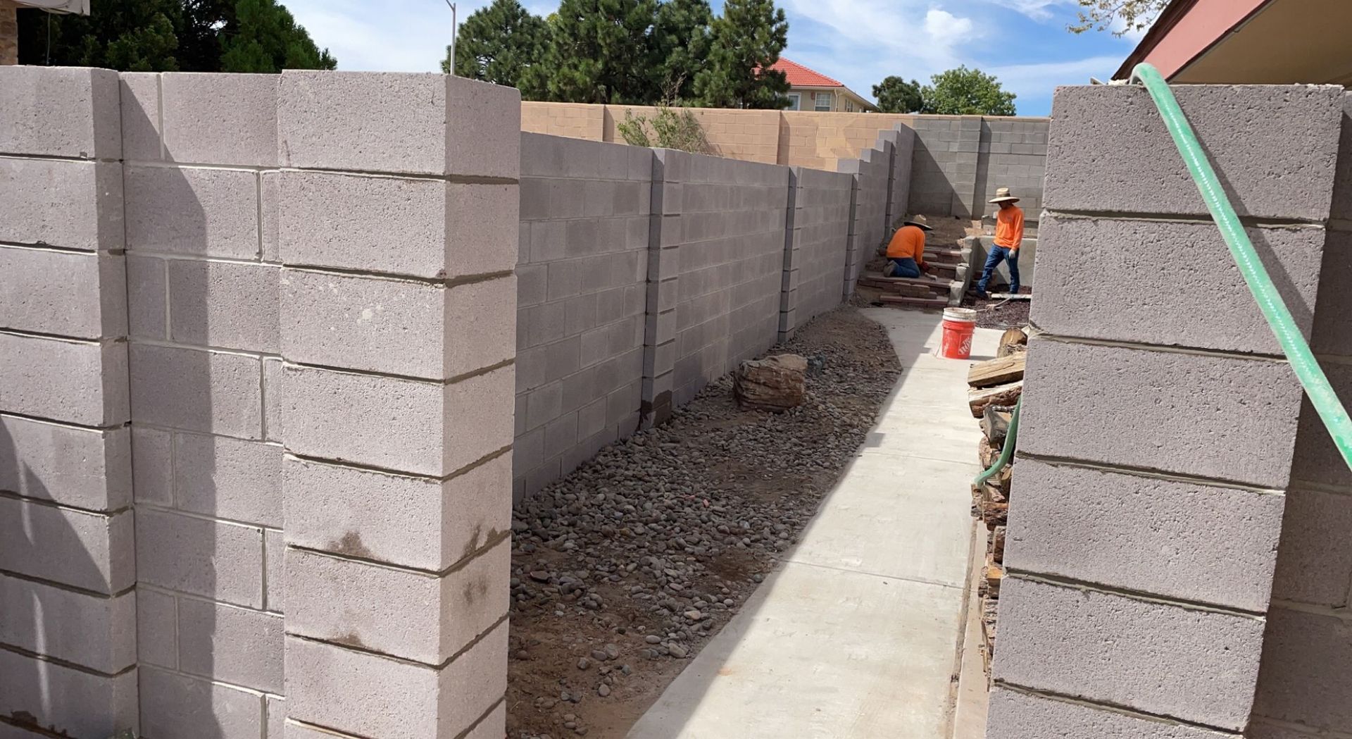 A brick wall is being built next to a sidewalk.