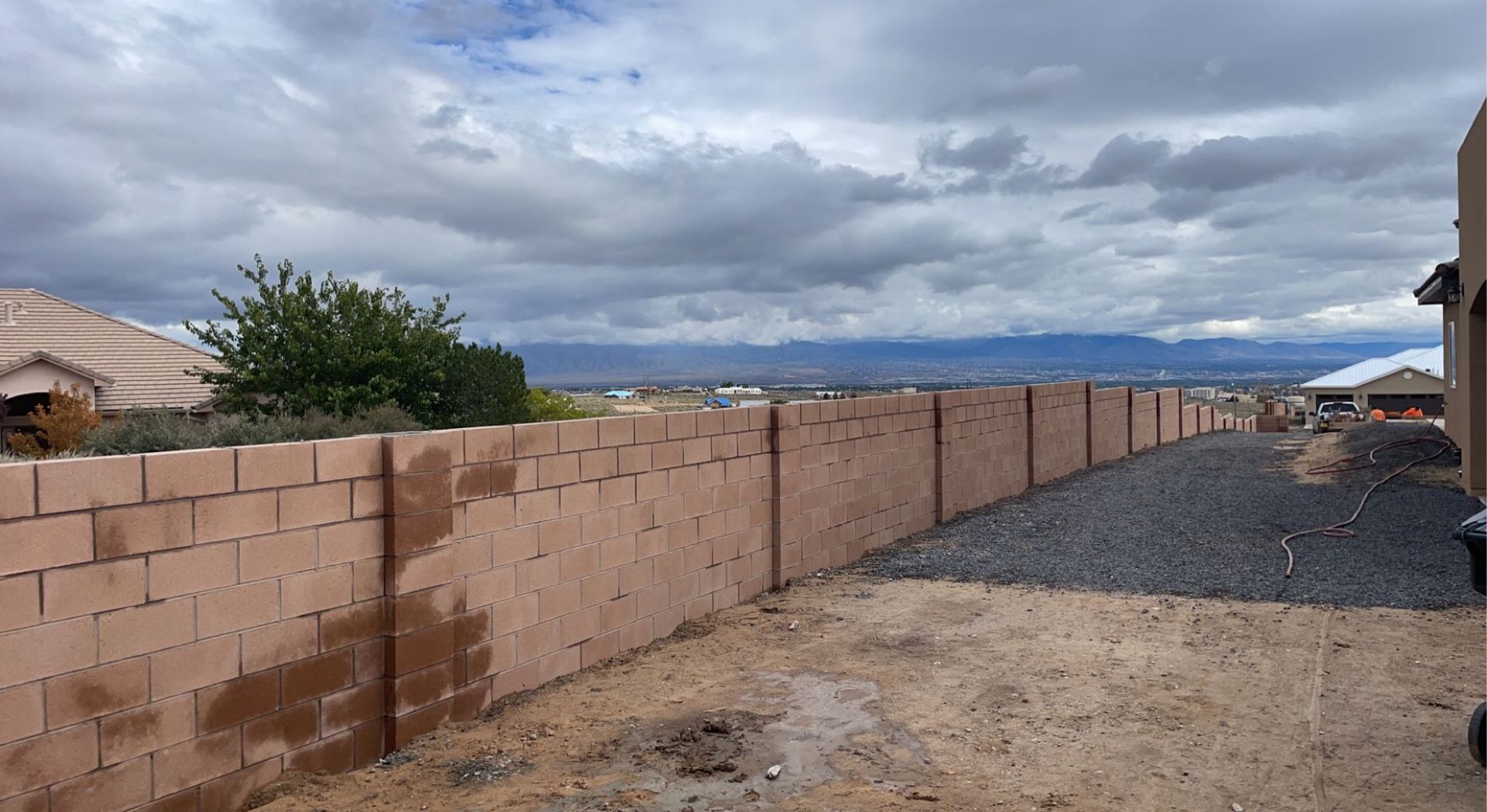 A brick fence surrounds a backyard with mountains in the background.