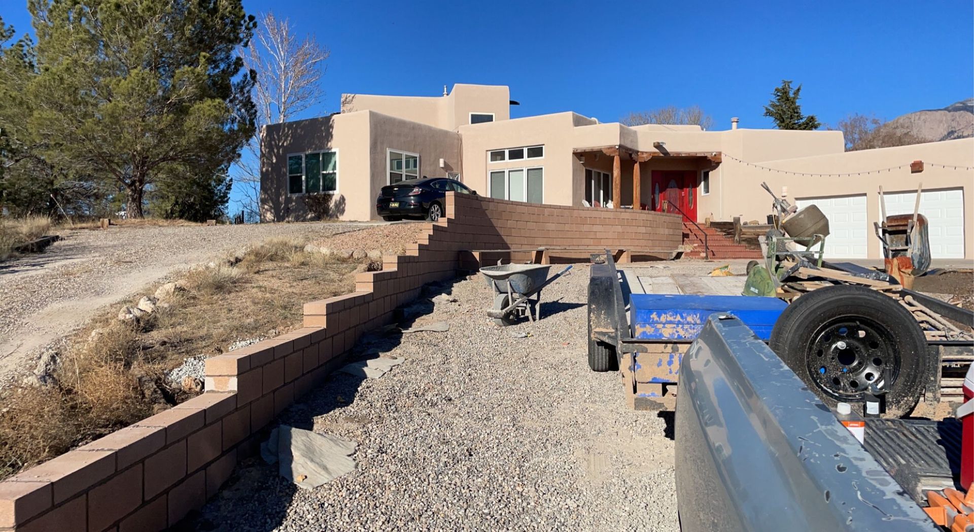 A large house is being built in the desert and a trailer is parked in front of it.