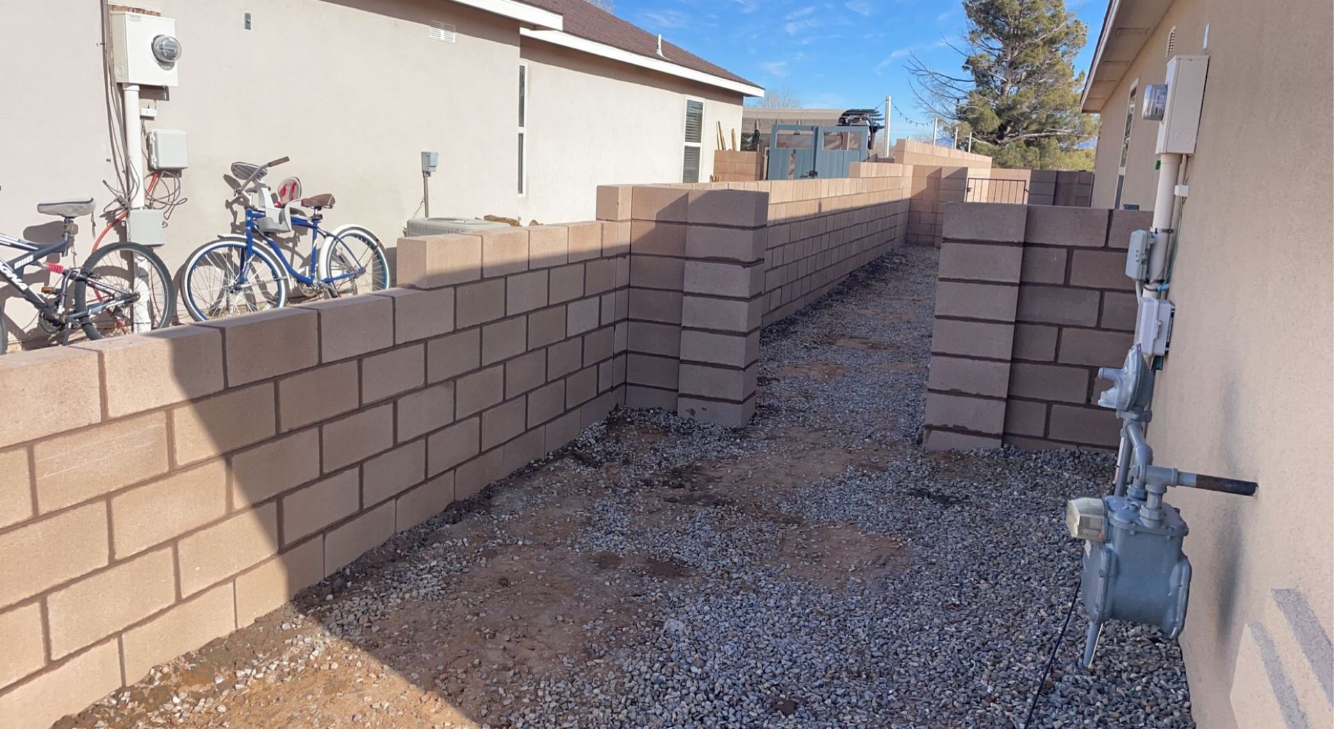 A brick wall is being built in the backyard of a house.