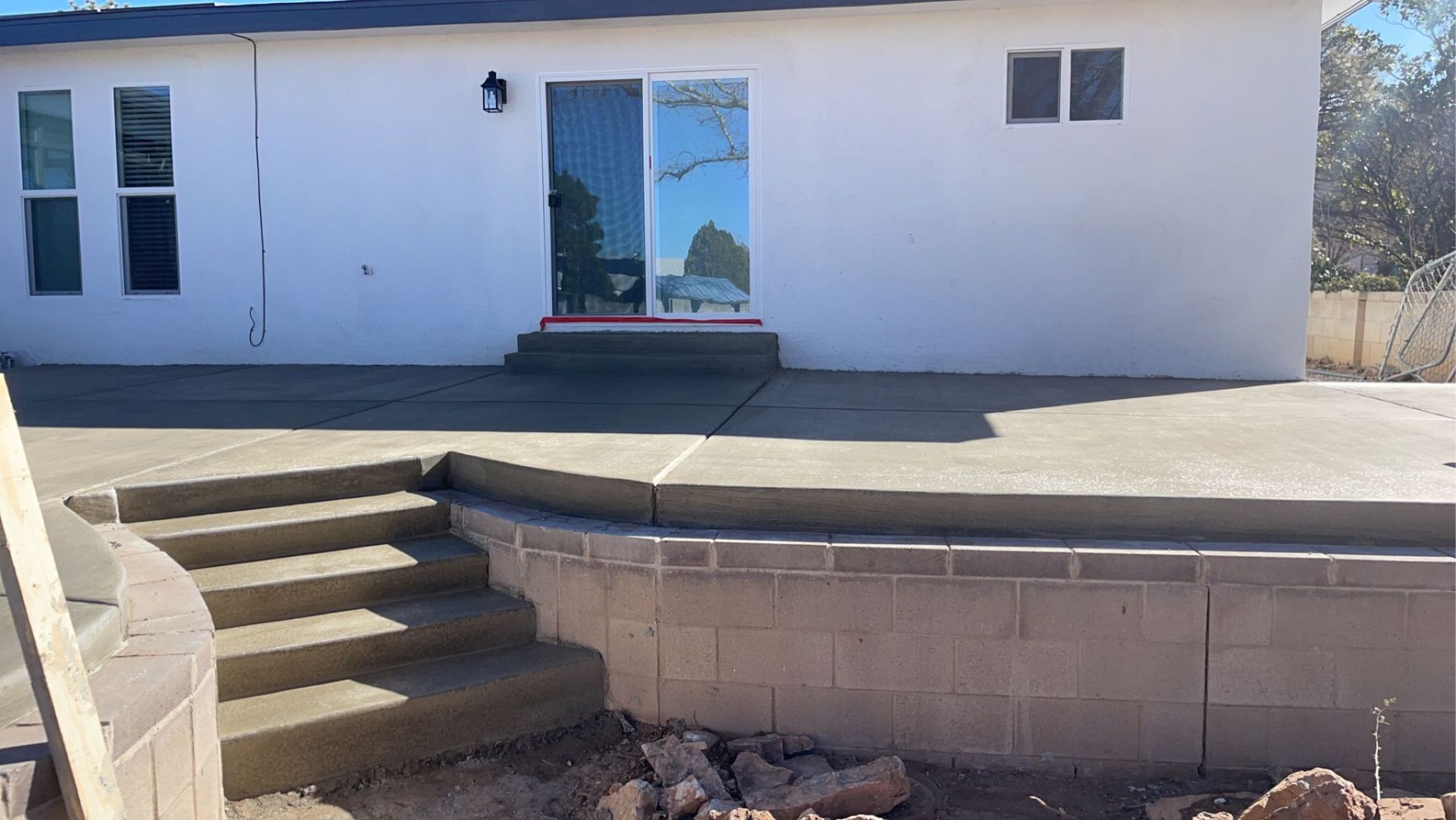 A white house with a concrete patio and stairs in front of it.