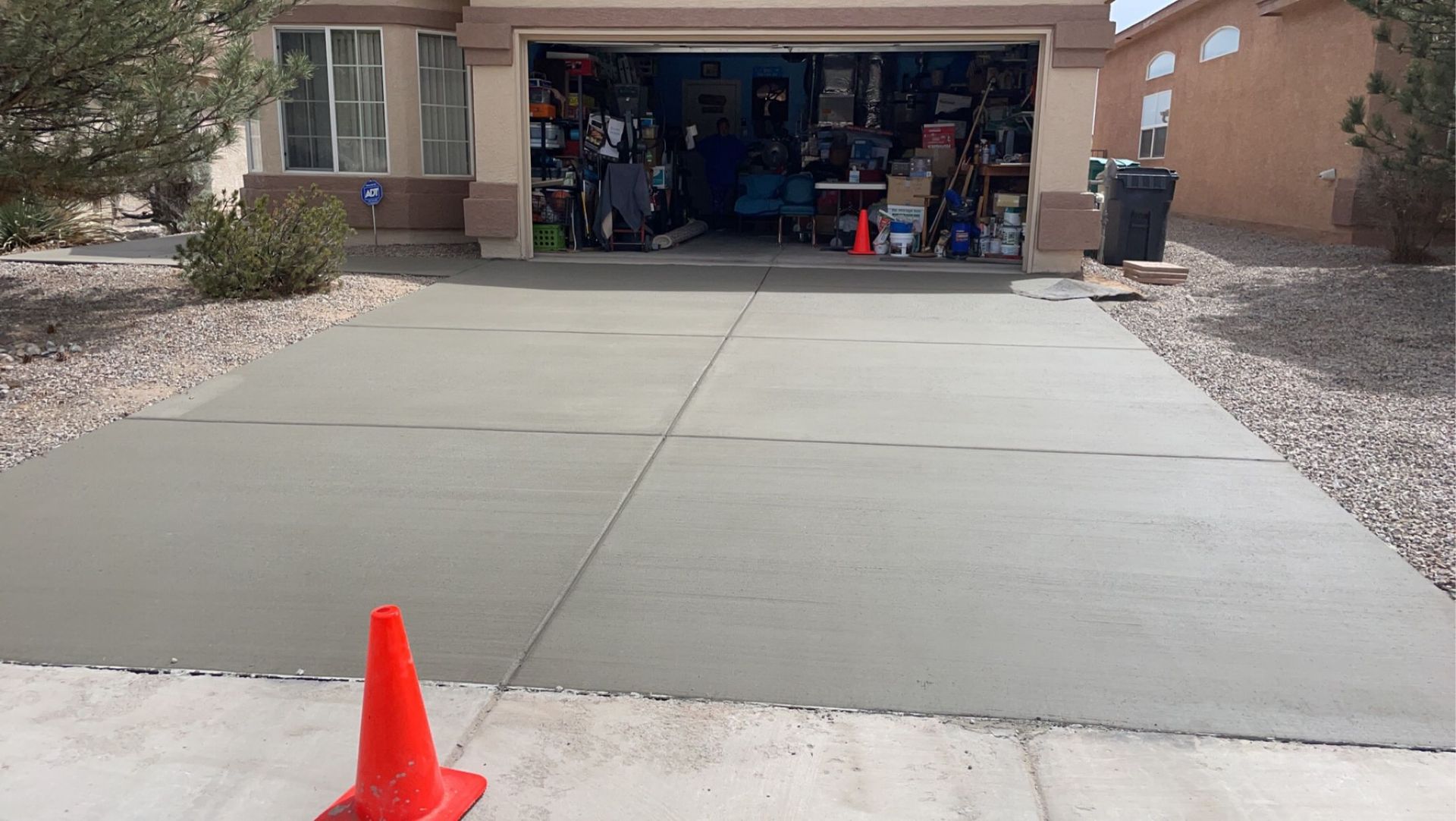 A concrete driveway with a red traffic cone in front of a garage.