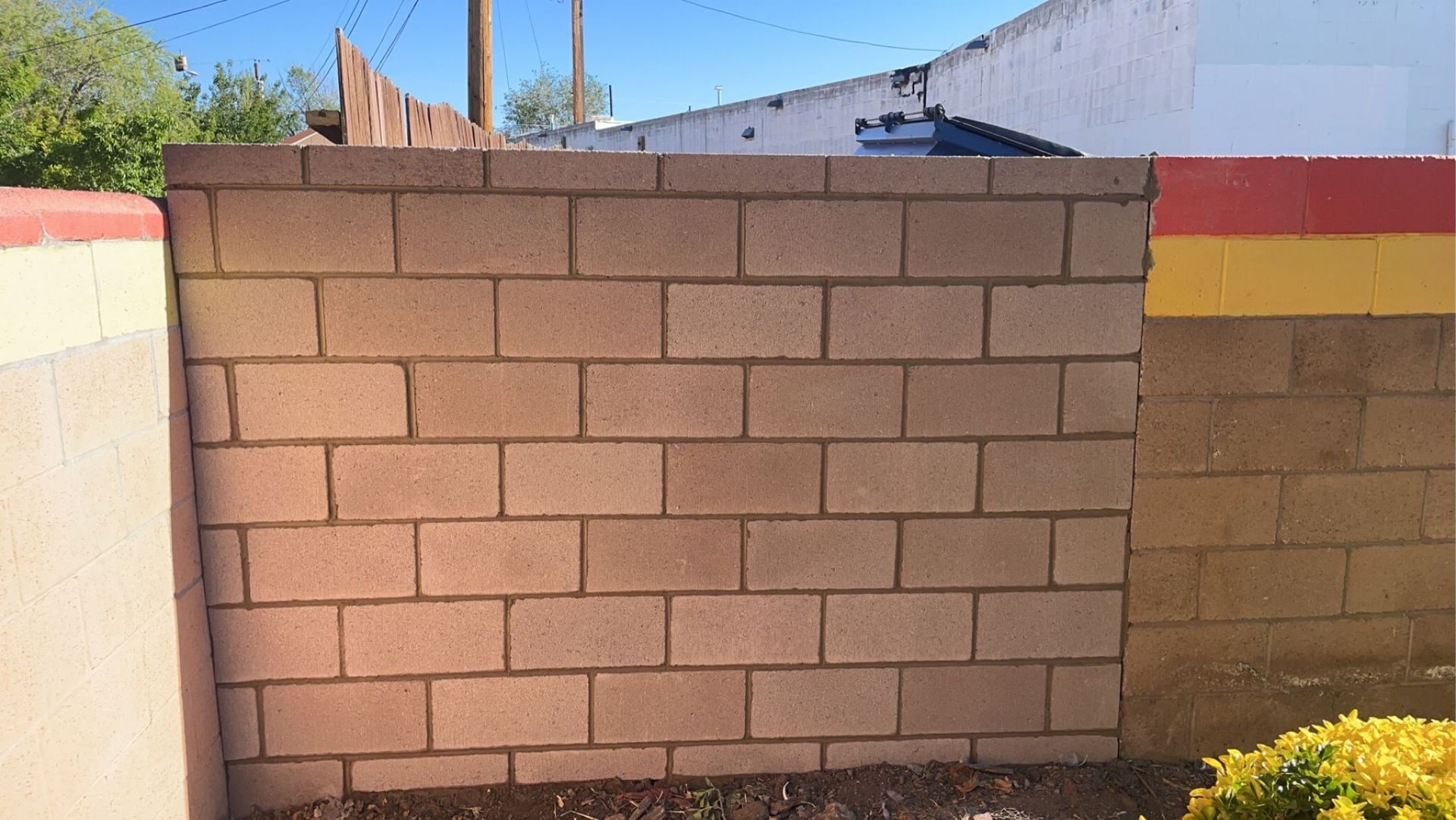 A brick wall with a red , white and yellow stripe painted on it.