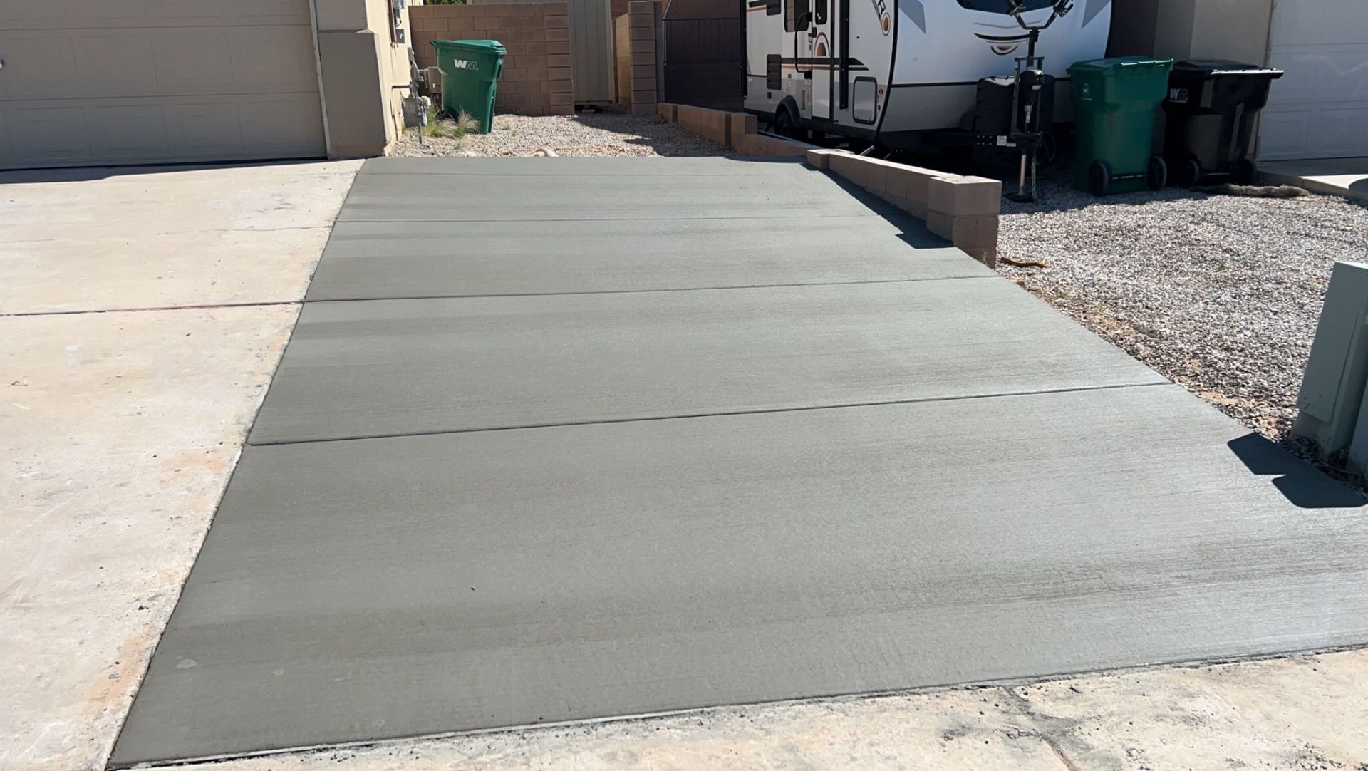A concrete driveway with a trailer parked in the background.