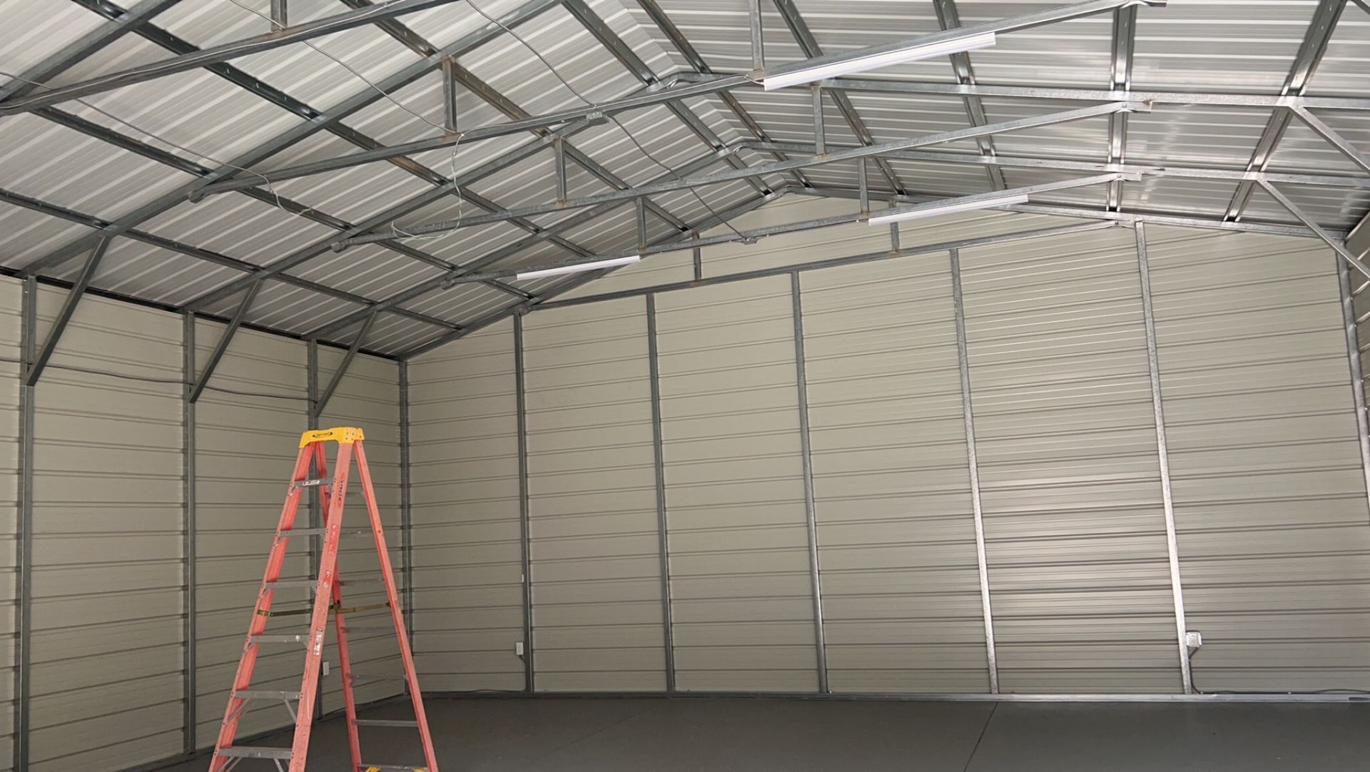 An empty garage with a ladder in the middle of it.