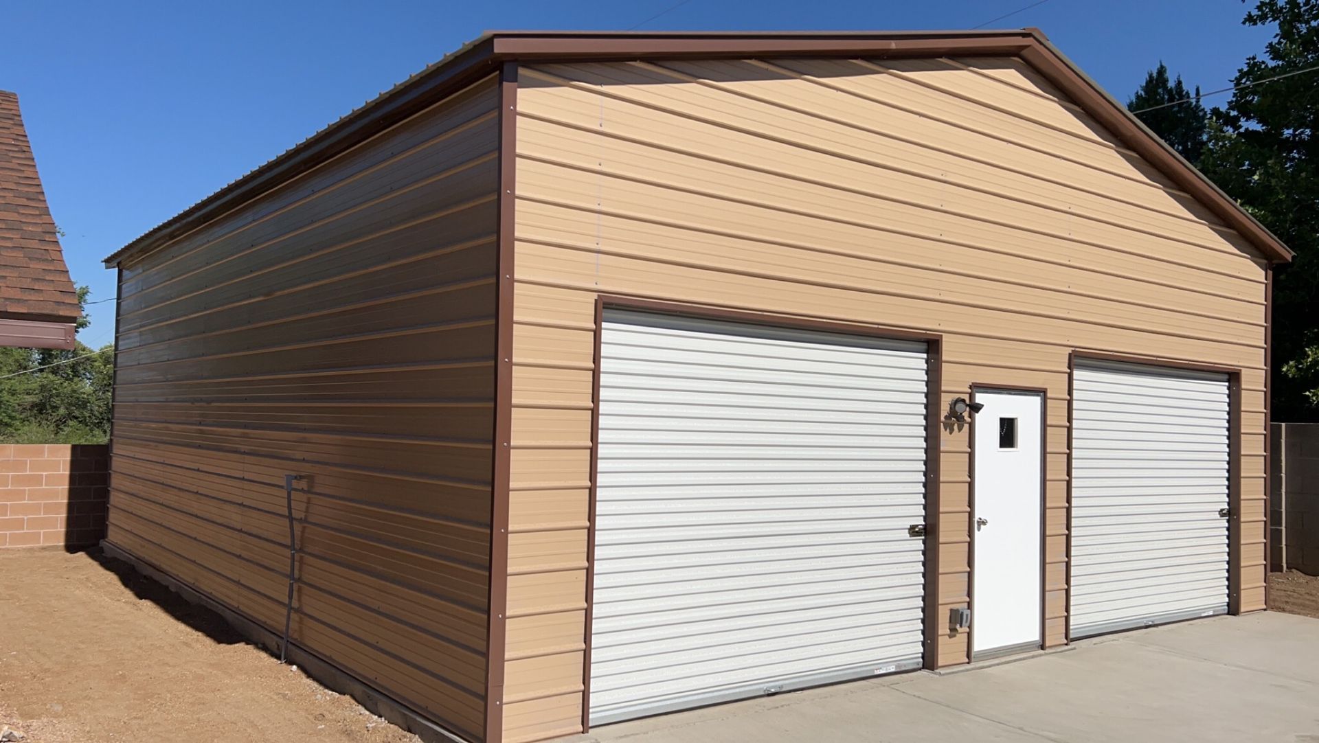 A brown garage with two white garage doors and a white door