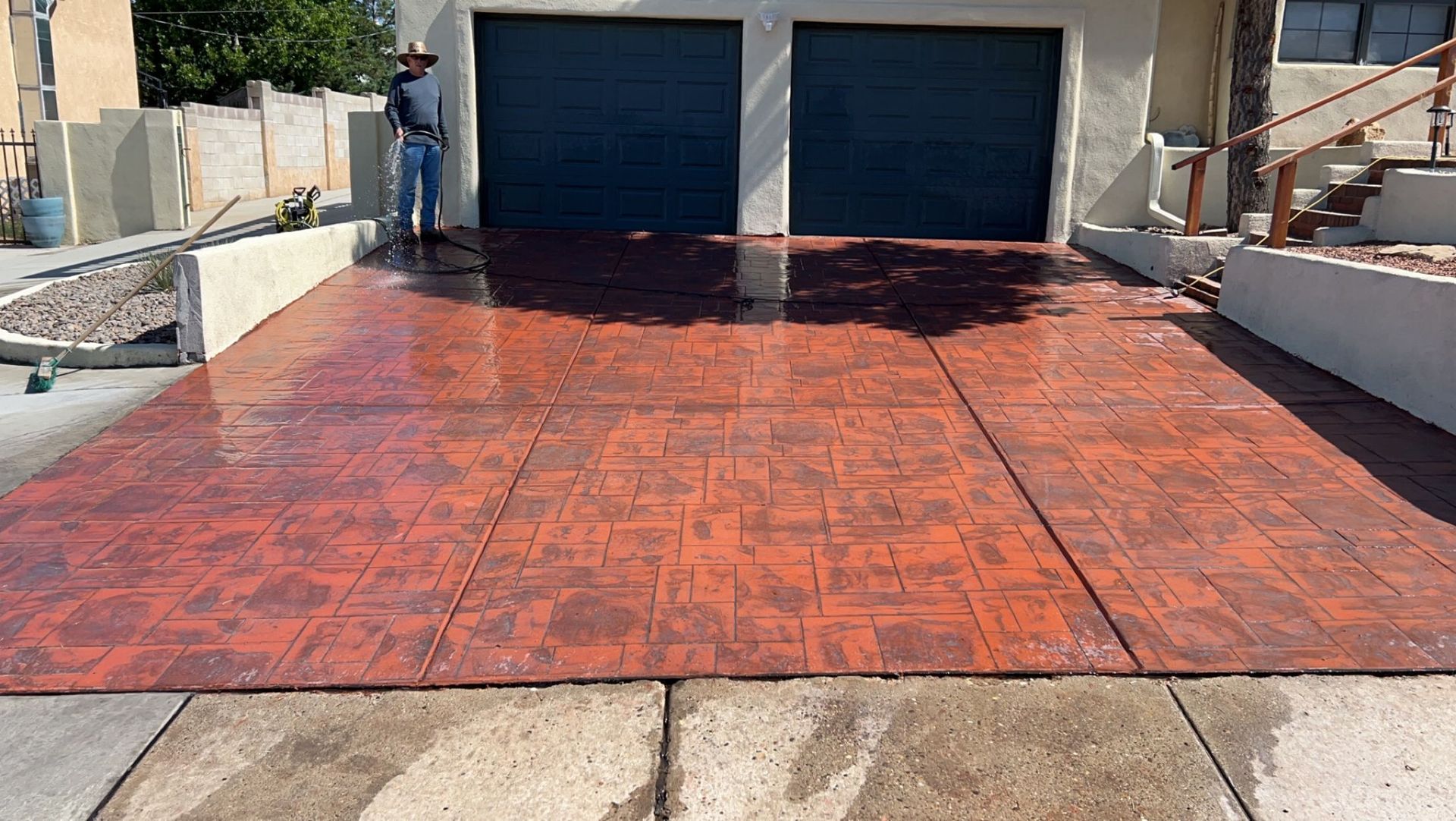 A man is standing on a brick driveway in front of a garage.
