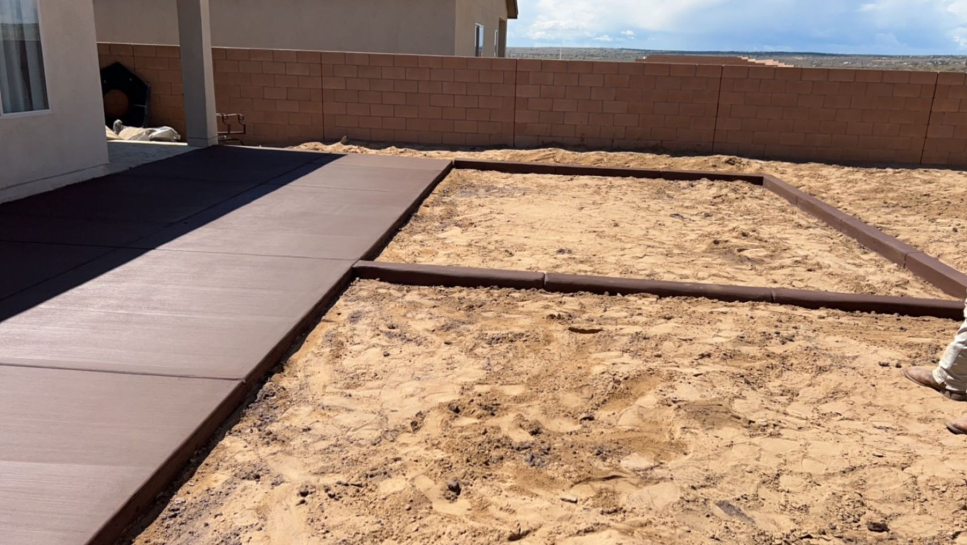 A sandbox is being built in the backyard of a house.