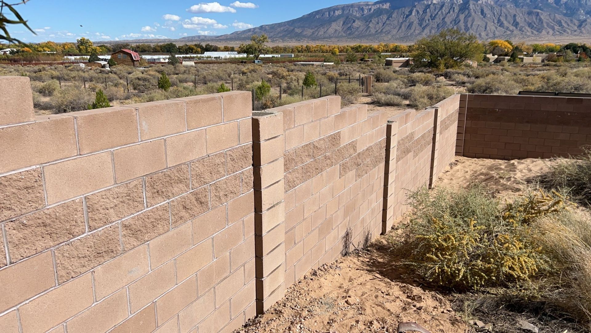 A brick wall in the middle of a desert with mountains in the background.