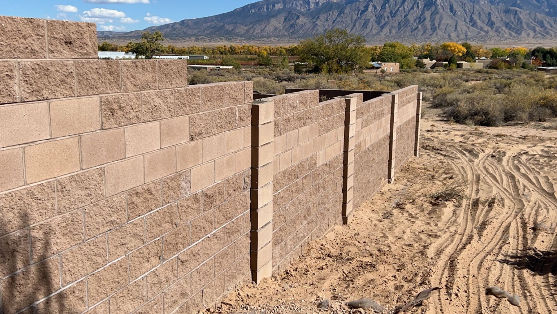 A brick wall in the middle of a desert with mountains in the background.
