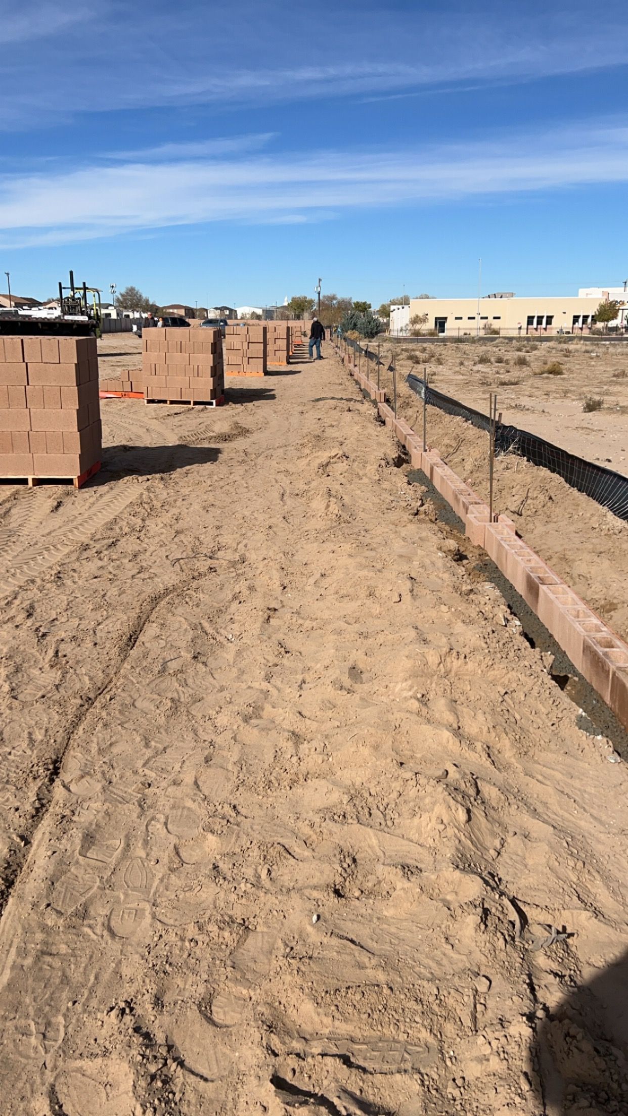 A dirt road leading to a building under construction.