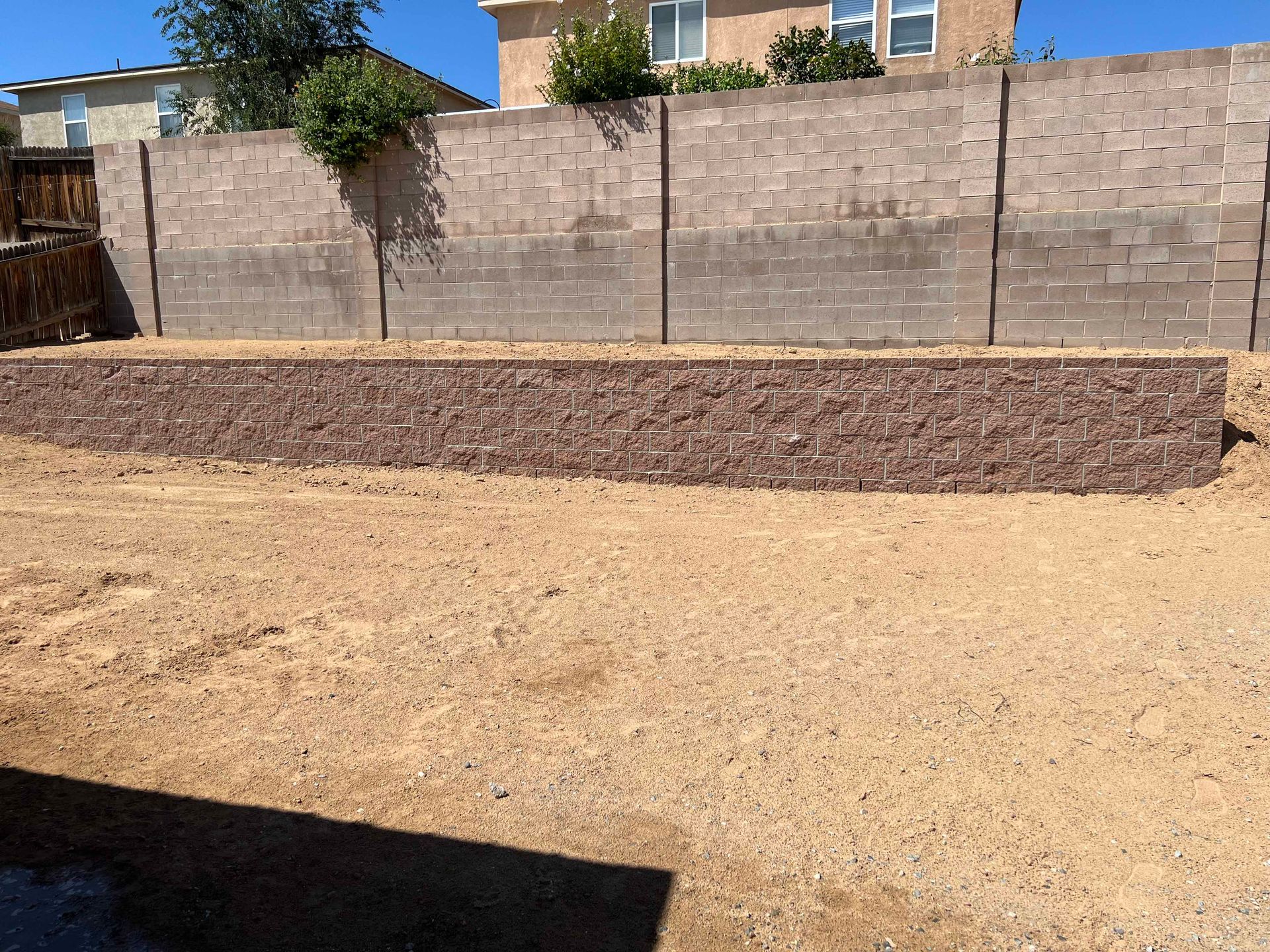 A backyard with a brick wall and a large pile of dirt