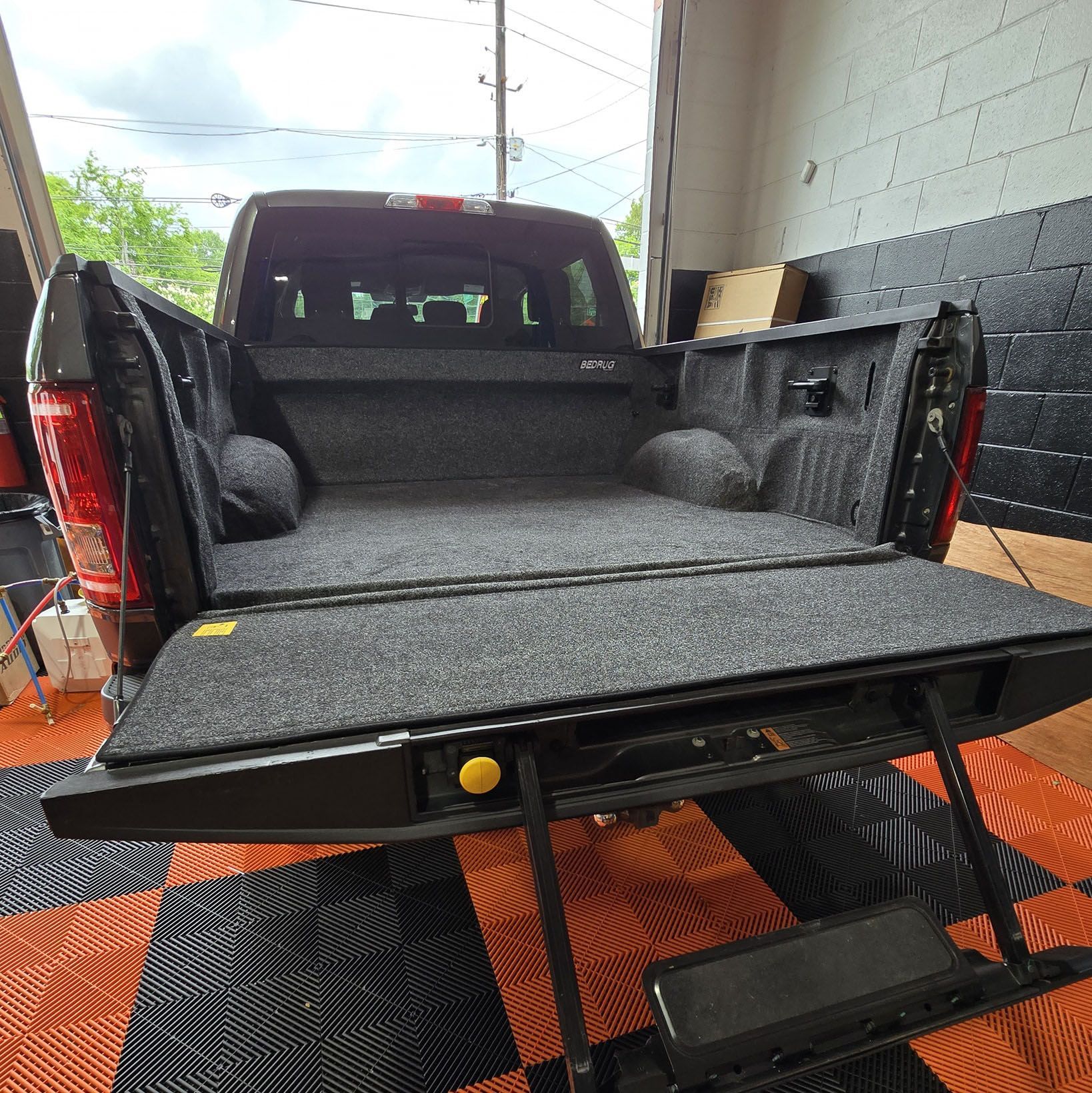 Black pickup truck bed with carpet, tailgate down, black and orange checkered floor.