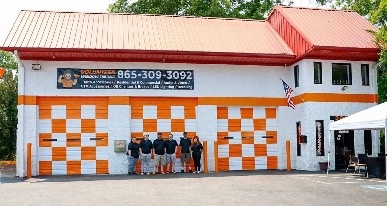 Orange and white checked building with a group of people posing in front. Sign displays a phone number.