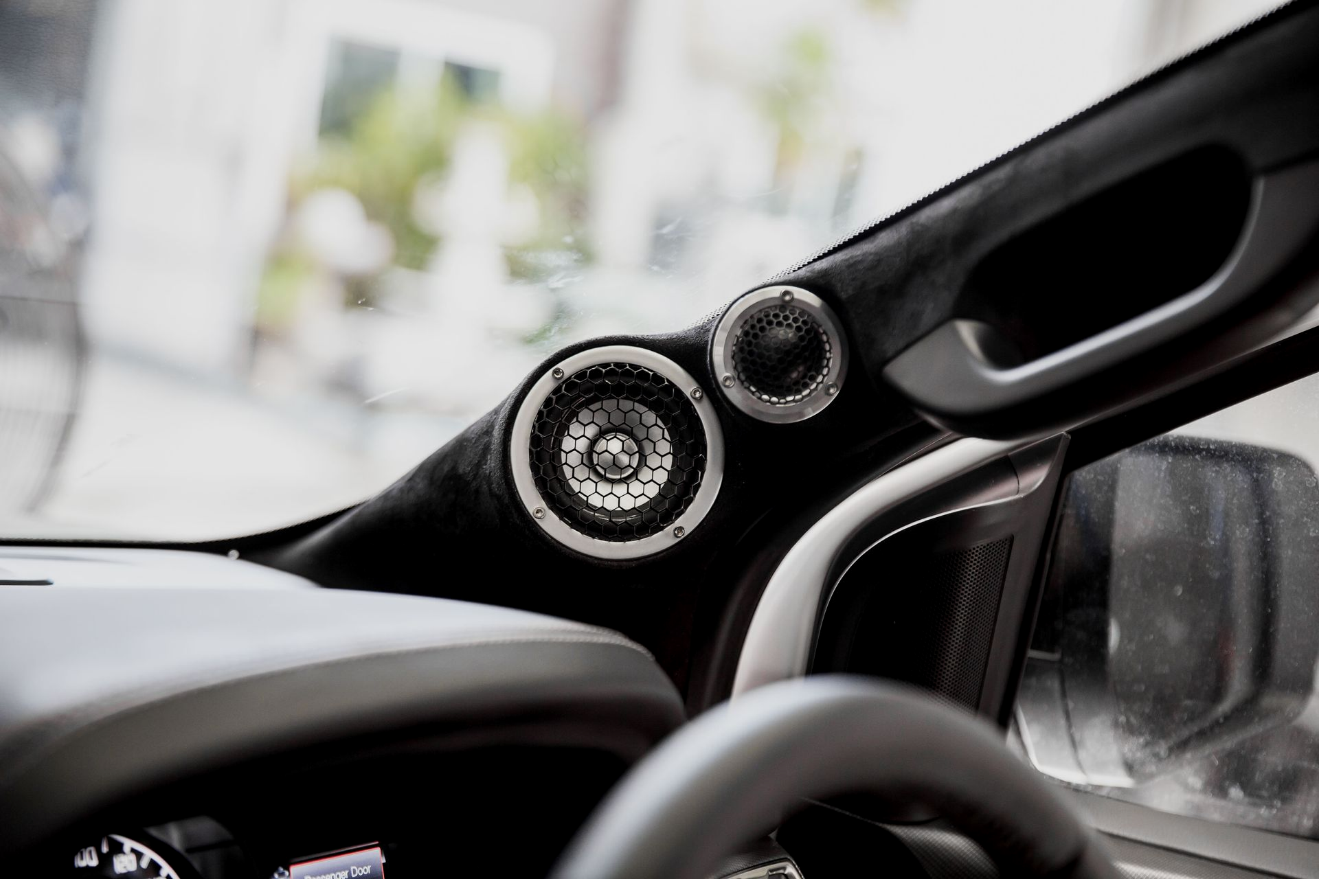 Car dashboard with speakers in a black trim near the windshield.