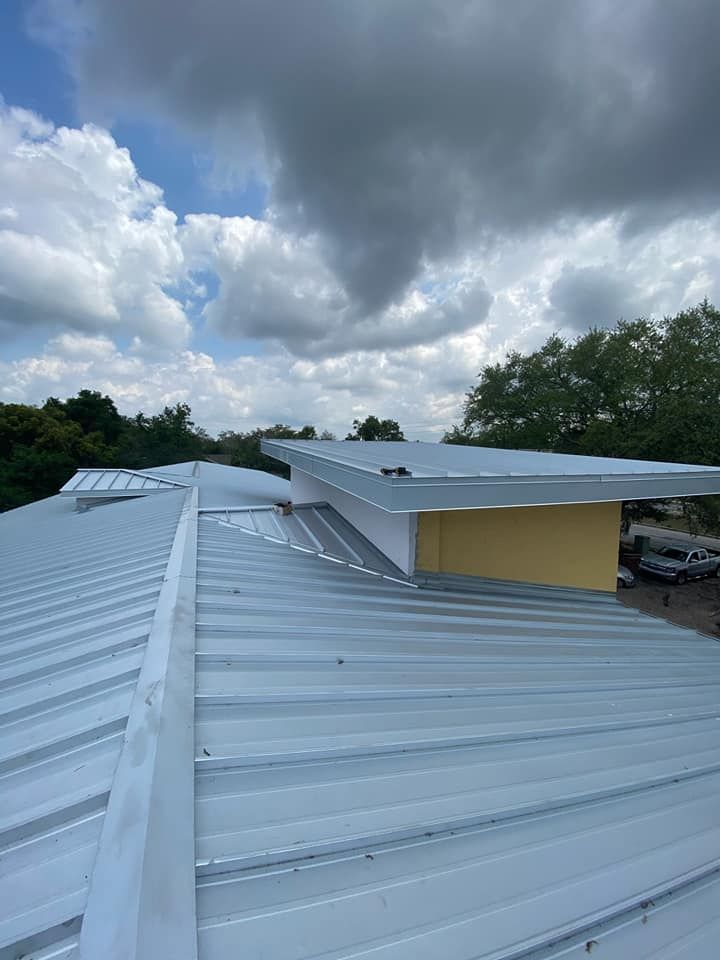 A white metal roof with a yellow building in the background.