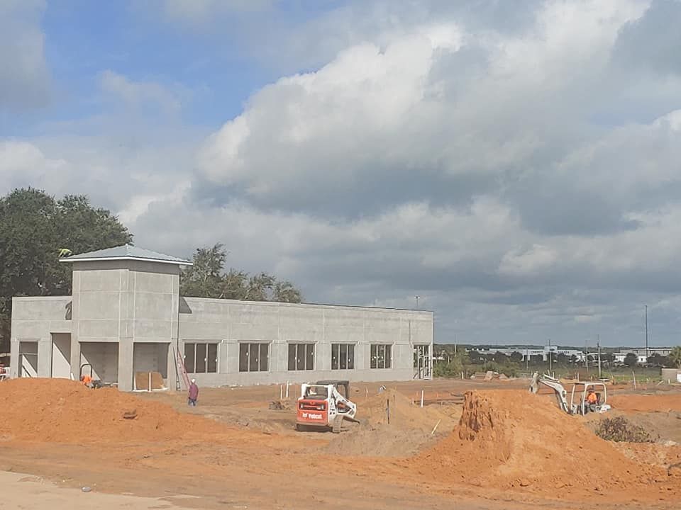 A large concrete building is being built in the middle of a dirt field.